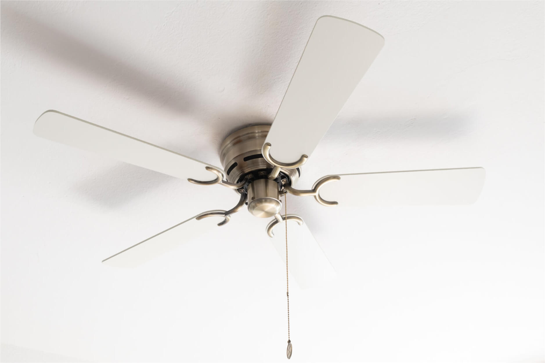 Deckenventilator mit fünf weißen Flügeln und zentraler Halterung an einer weißen Decke.