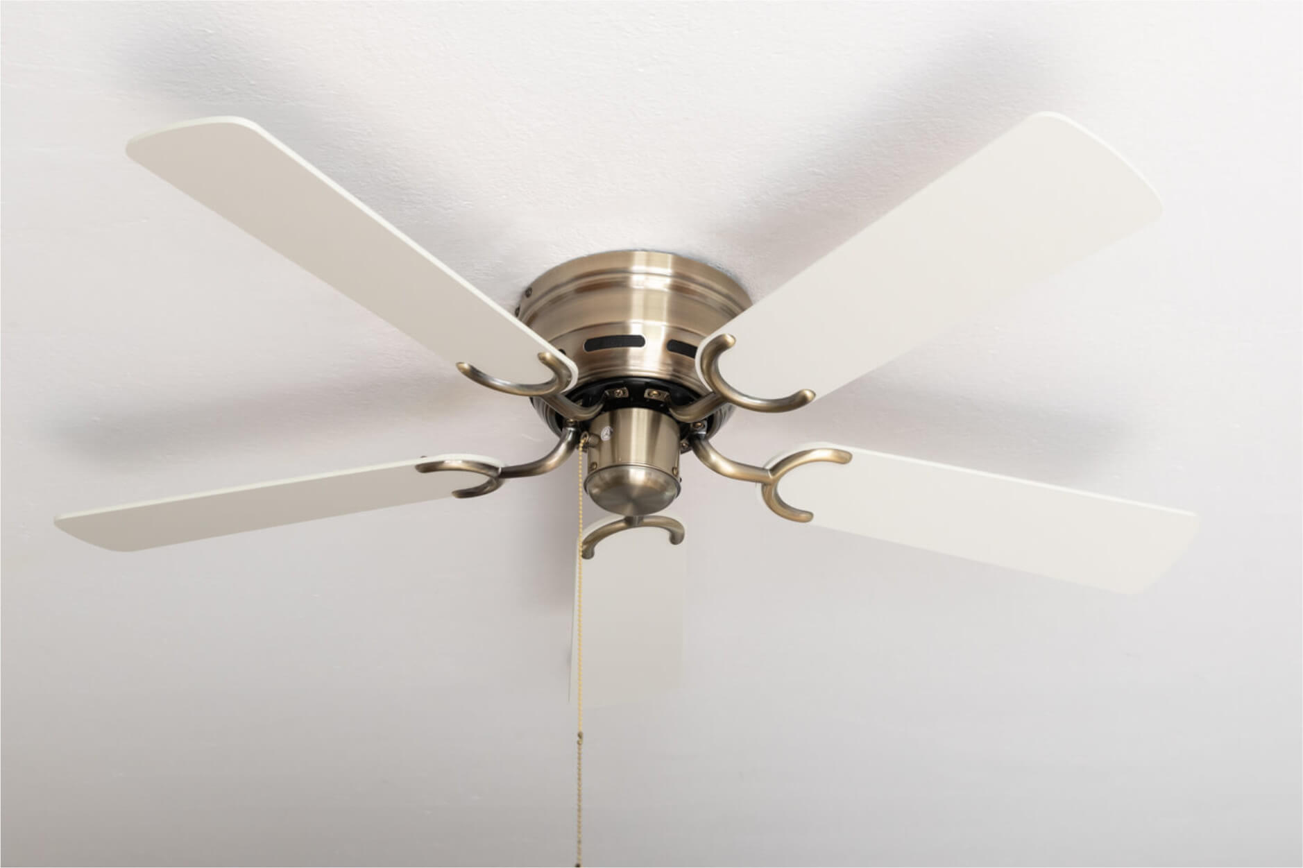 Ein Deckenventilator mit weißen Flügeln und Messingfinish.