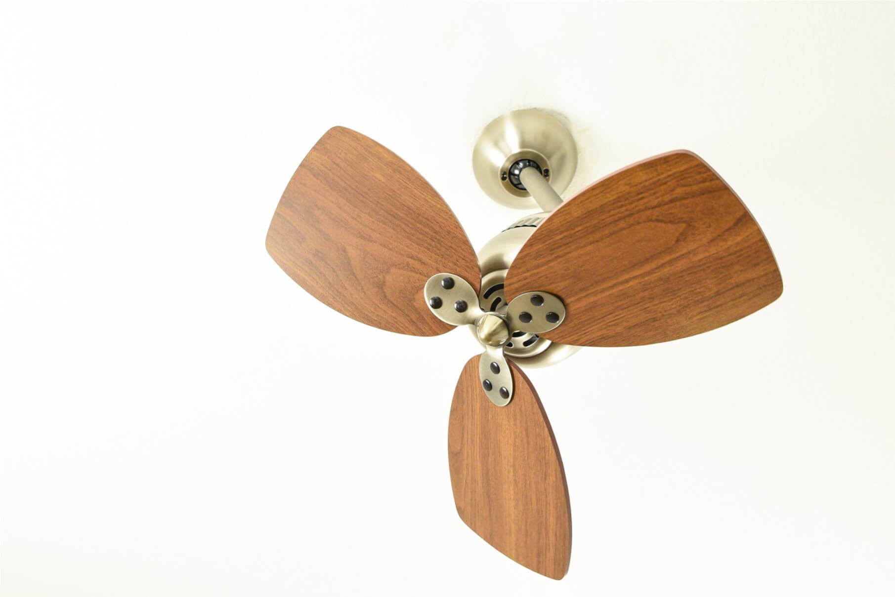 Ventilatore da soffitto con pale in legno e finitura argentata, visto dal basso.