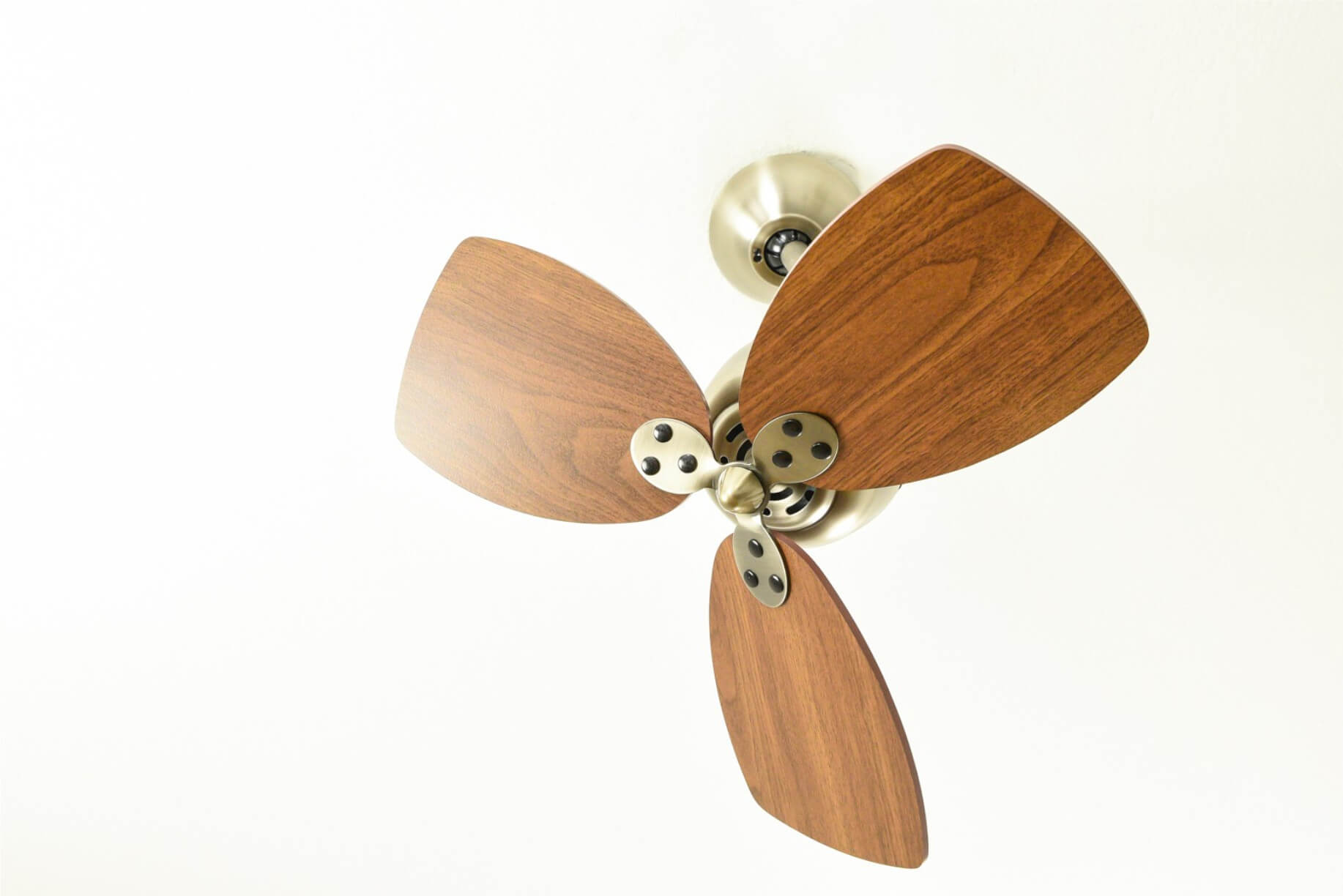 Deckenventilator mit drei Holzblättern und weißem Deckenhintergrund.