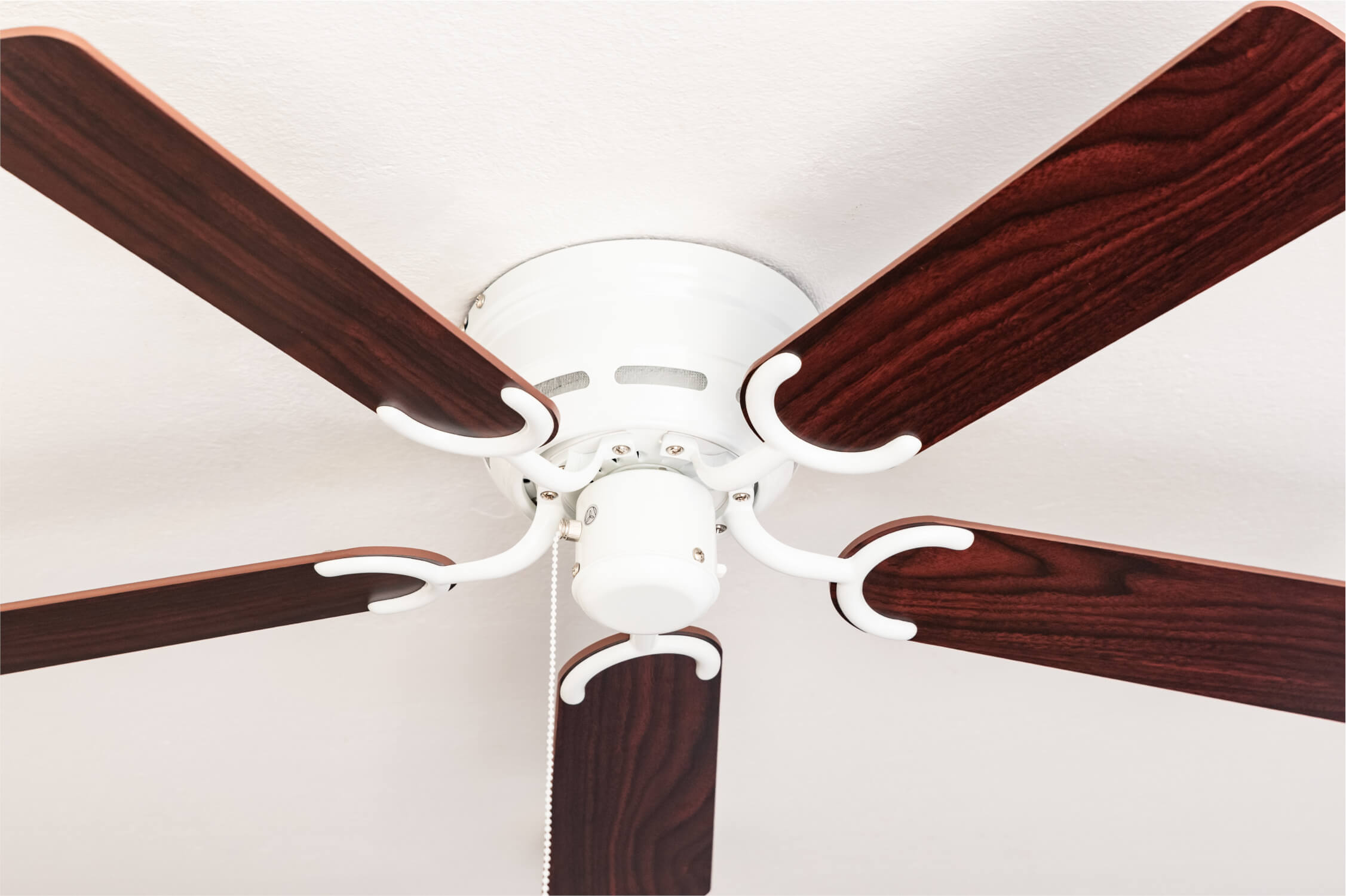 Deckenventilator mit fünf Holzblättern. Weißer Sockel und Arme.