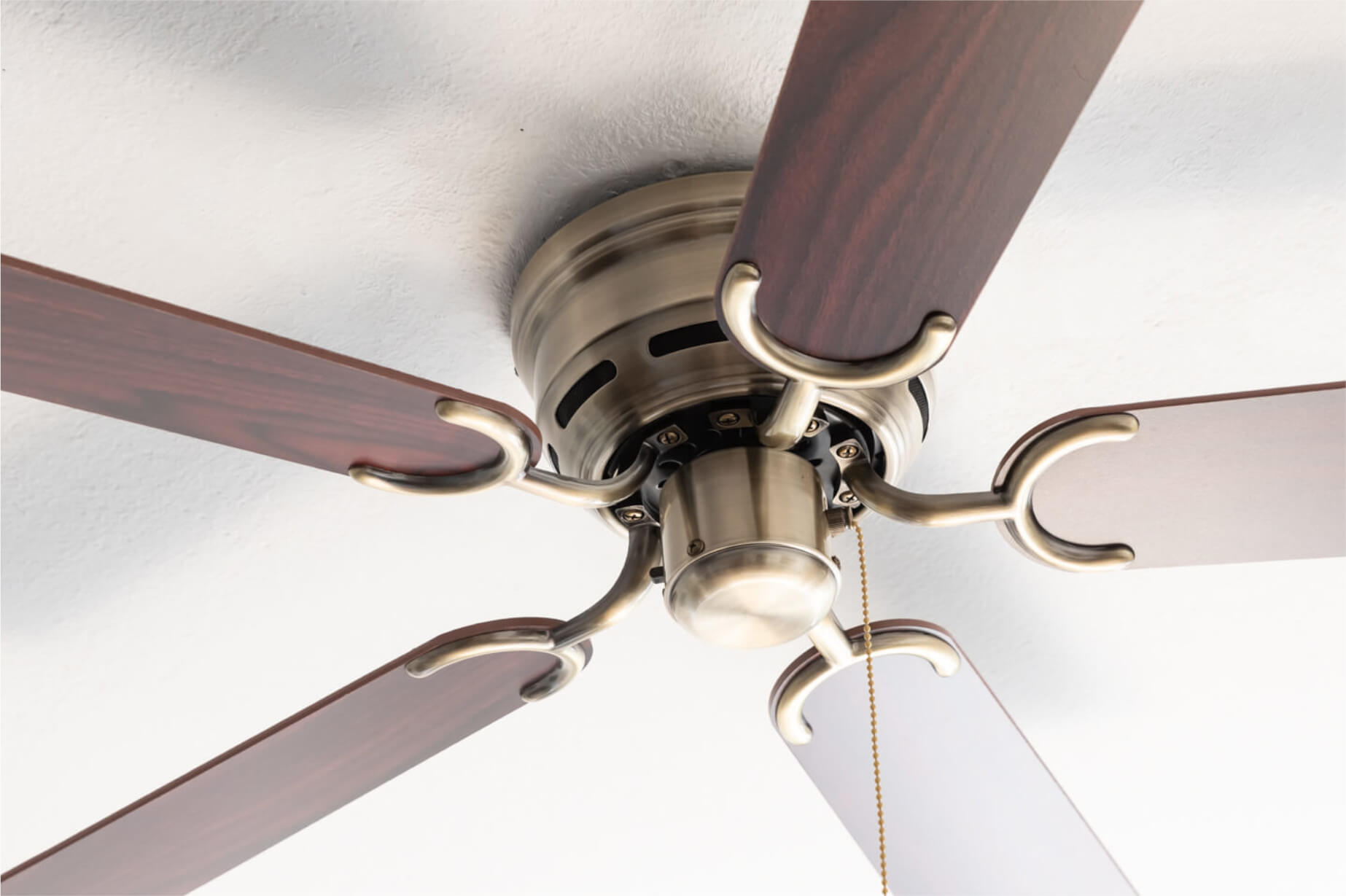 Deckenventilator mit fünf Holzblättern und Messingfarbenem Motorgehäuse.