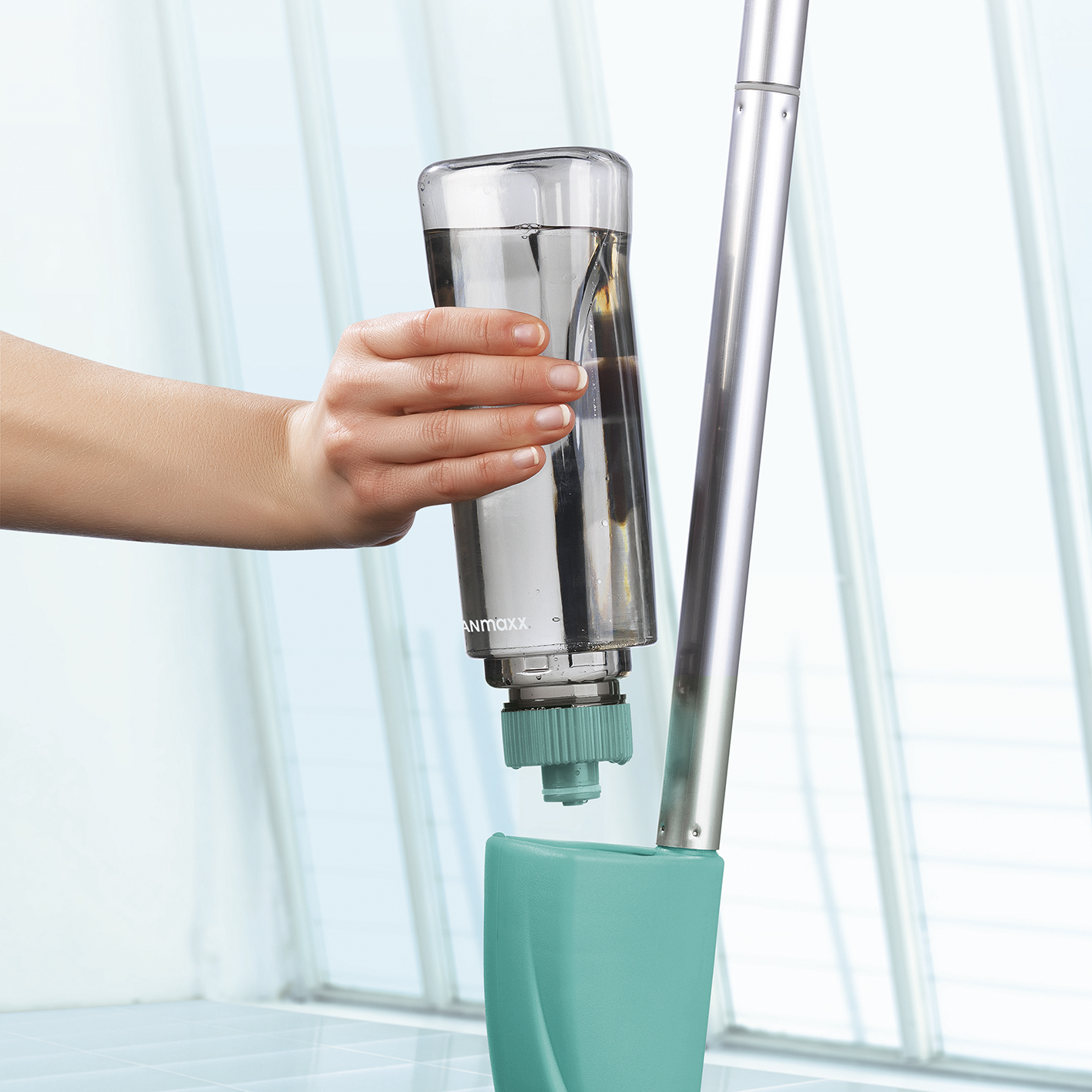 Eine Hand hält eine Wasserflasche, um Wasser in ein Reinigungsgerät zu gießen.