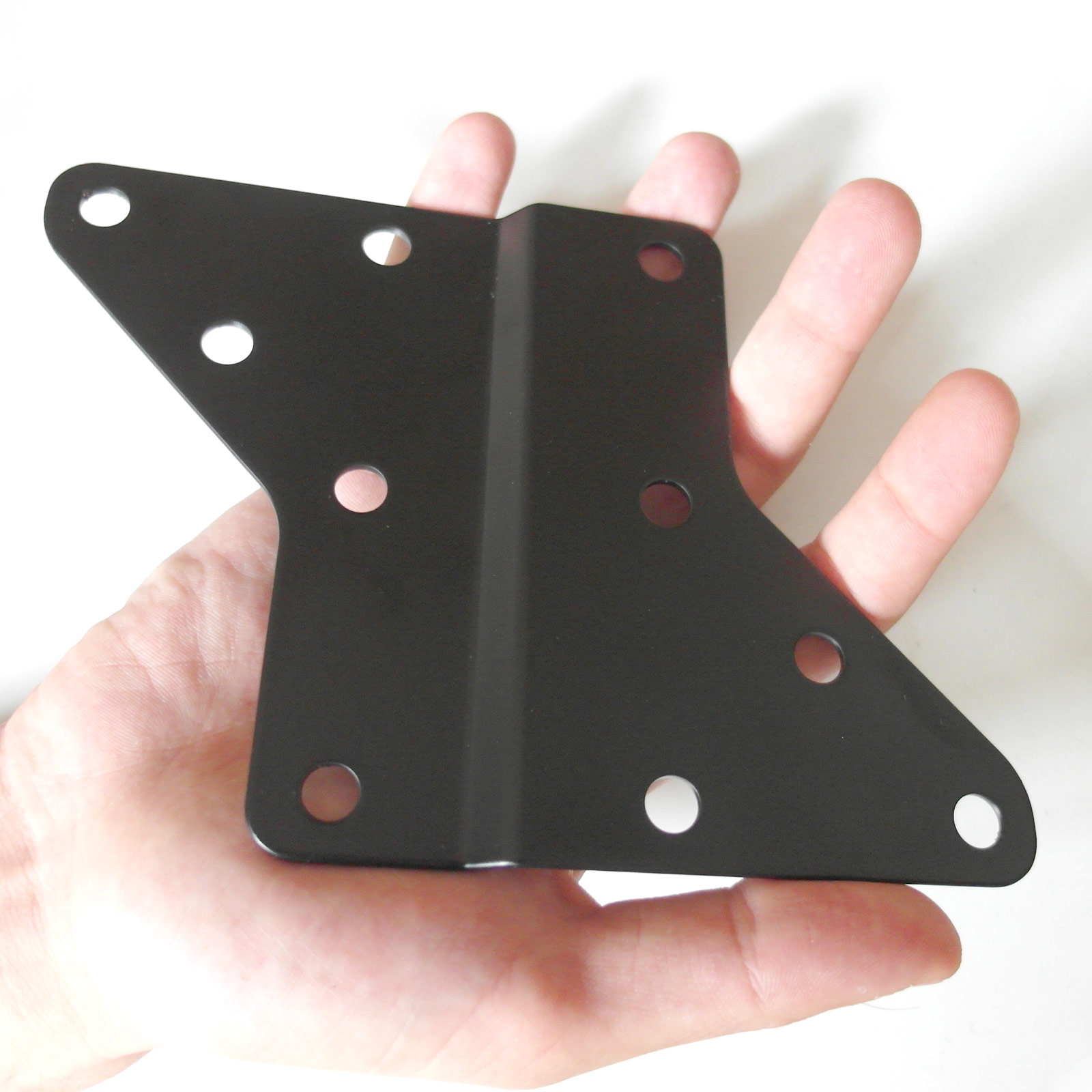 Schwarze Metallhalterung in einer menschlichen Hand. Mehrere Löcher. Weißer Hintergrund.
