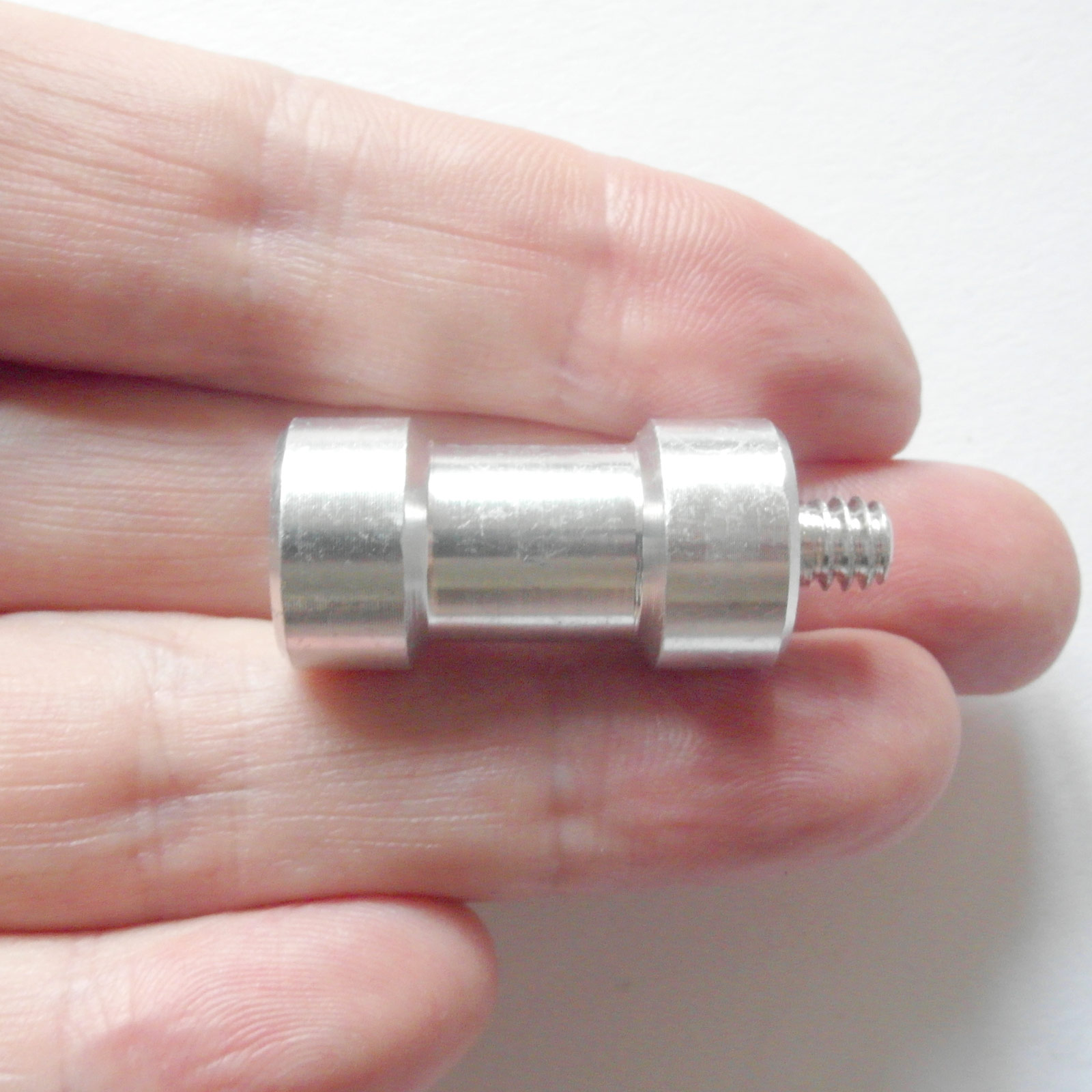 Silbernes Metallobjekt, das in einer Hand gehalten wird. Das Objekt hat ein Gewindeende. Weißer Hintergrund.