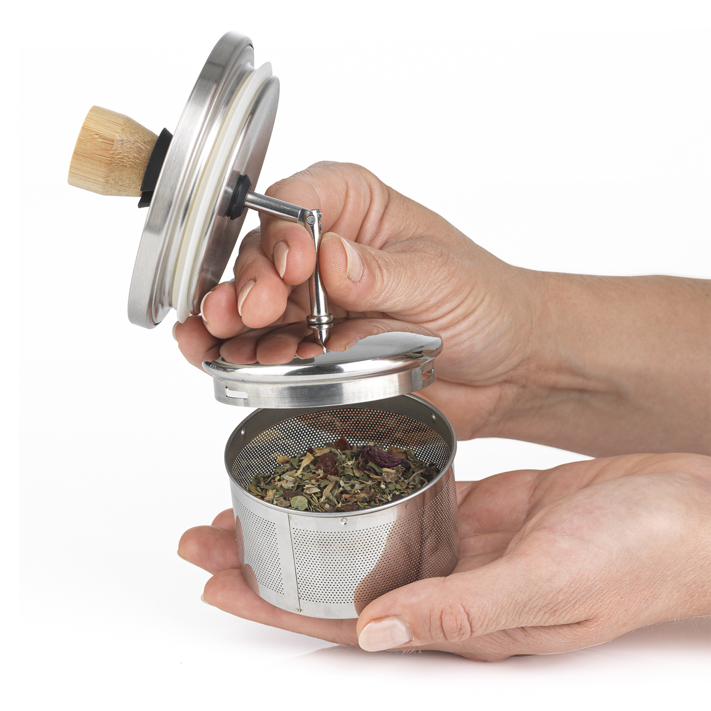 Hände halten einen Tee-Infuser mit Kräutern.