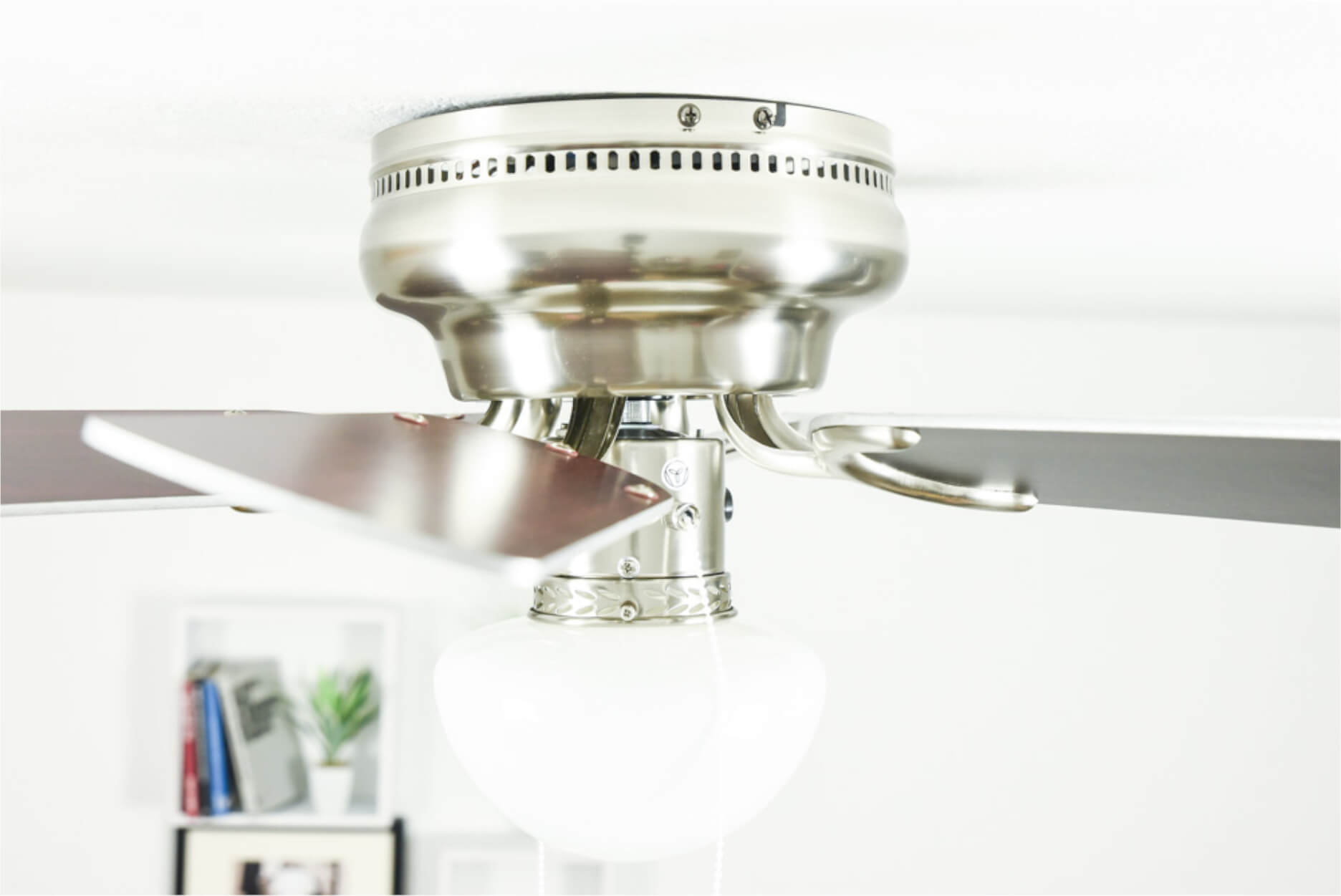Deckenventilator mit weißen Flügeln, gebürsteter Nickel-Oberfläche und zentraler Leuchte.