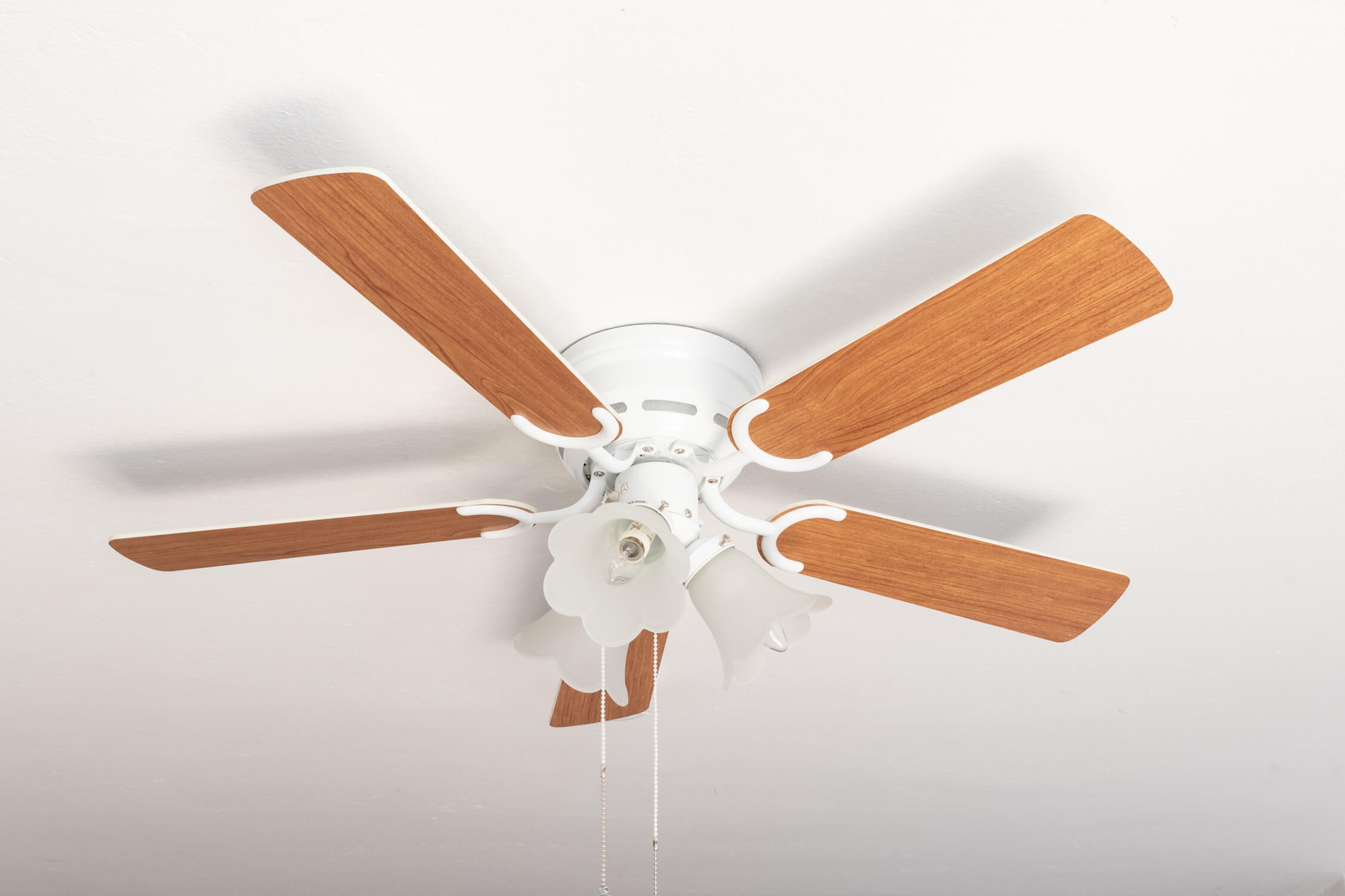 Ventilatore da soffitto bianco con pale in legno, cinque pale. Lampada sotto.