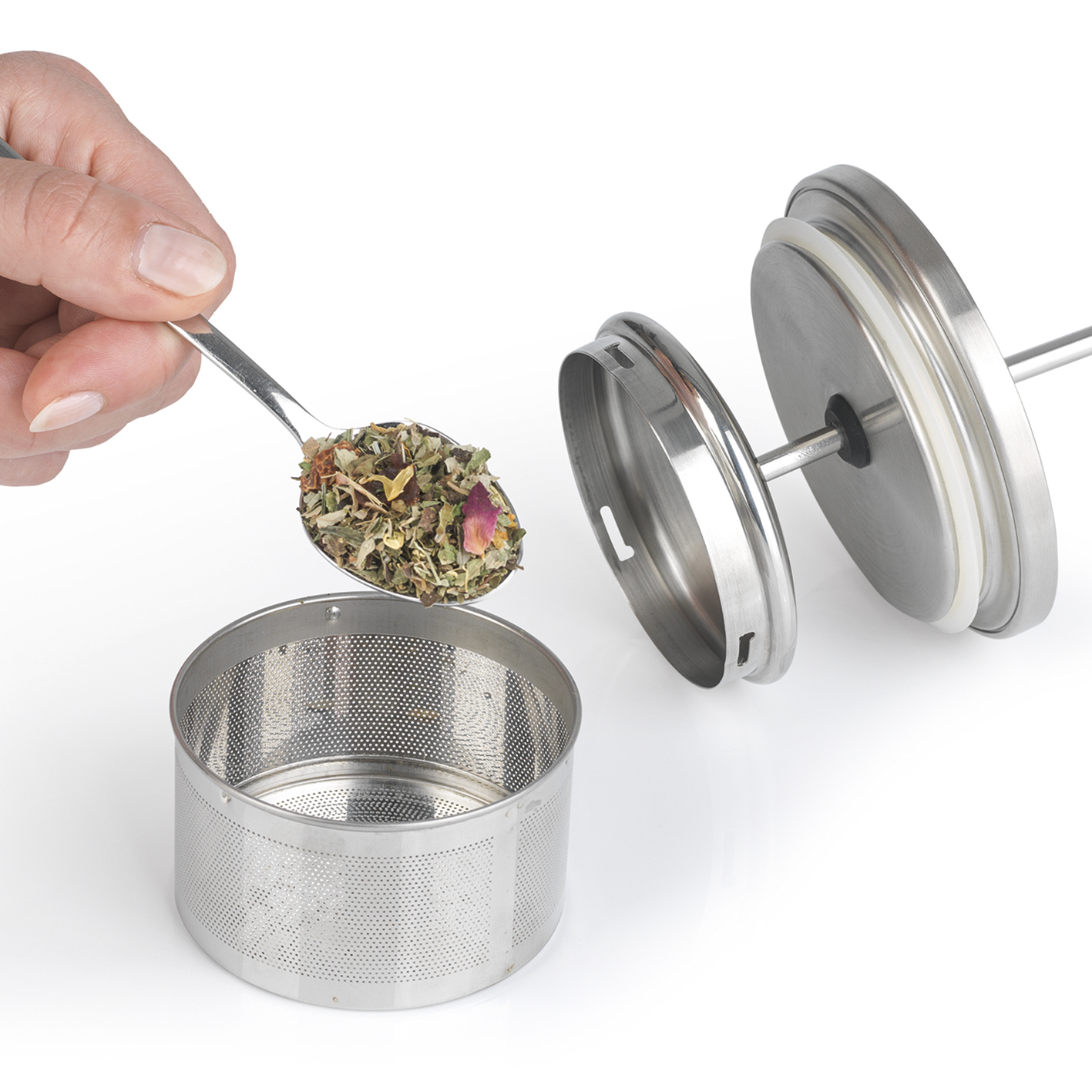 Eine Hand mit einem Löffel gießt Teeblätter in einen Edelstahl-Infuser.