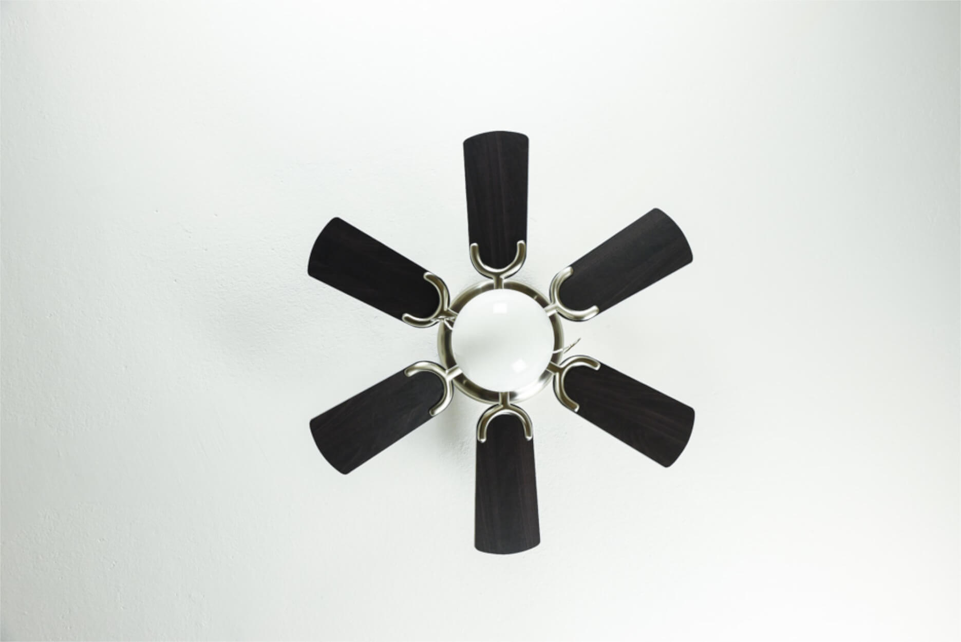Ansicht eines Deckenventilators mit sechs schwarzen Flügeln und einer zentralen Leuchte.