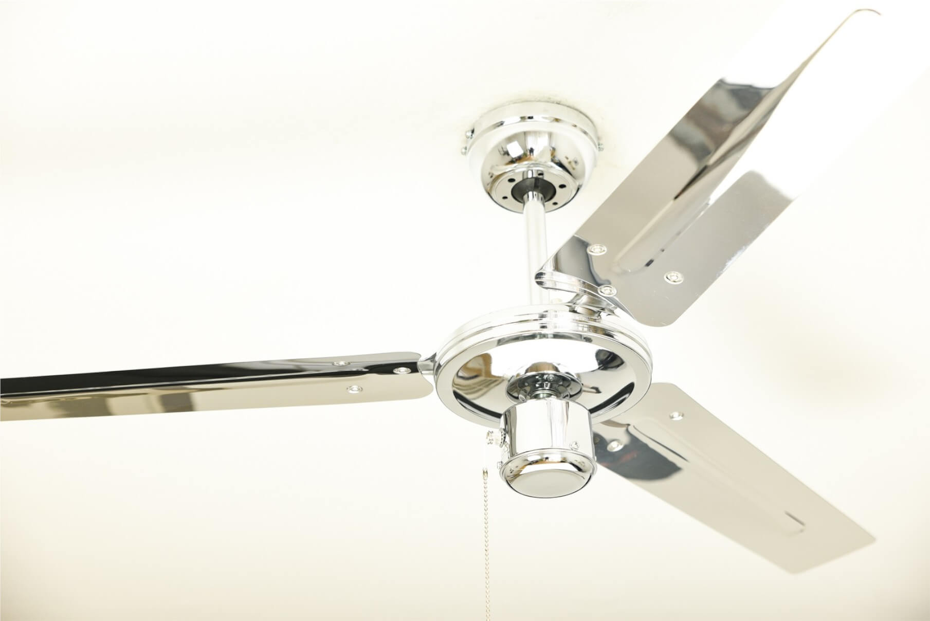 Chrom Deckenventilator mit drei Flügeln. Weißer Deckenhintergrund. Der Ventilator ist zentriert.