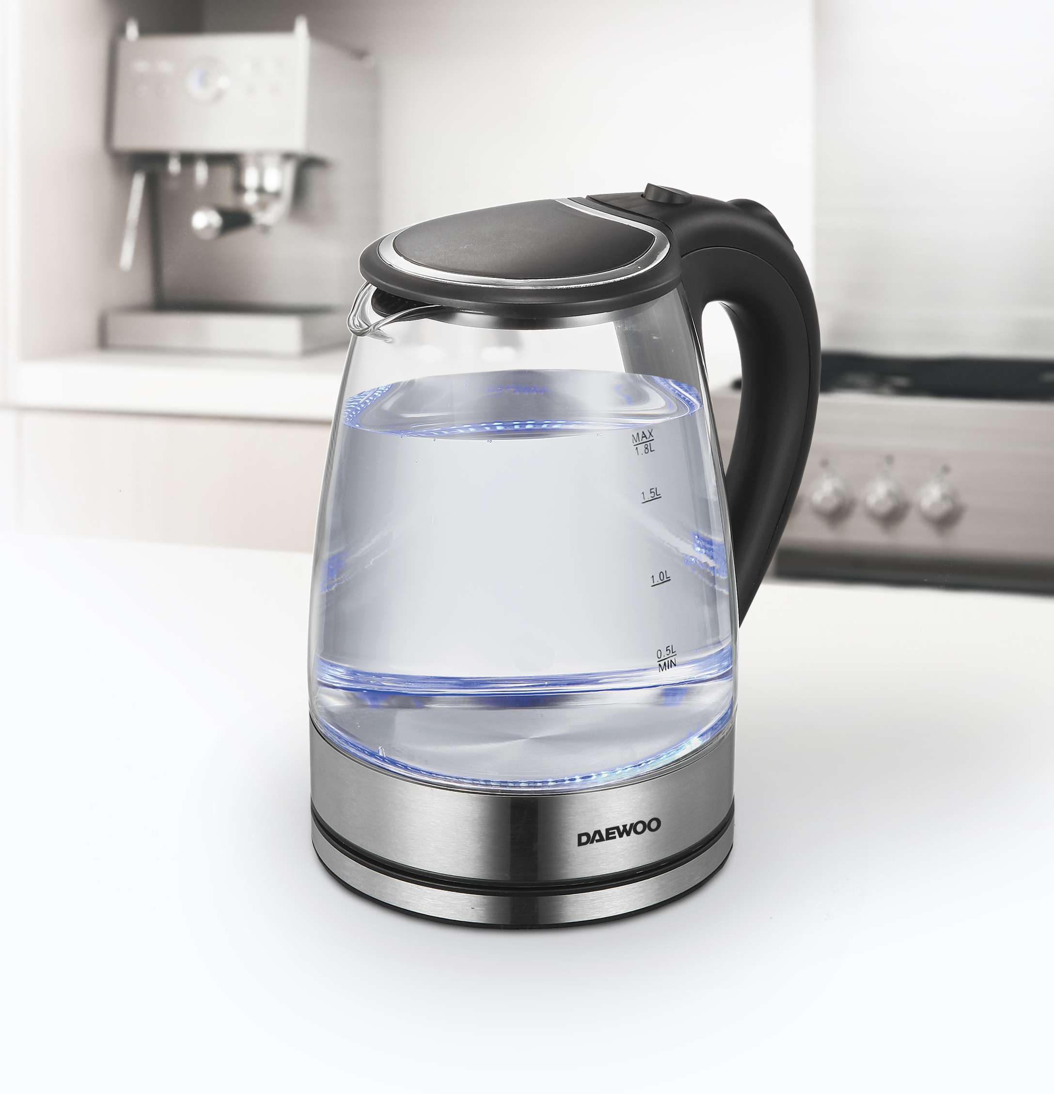 Elektrischer Glaskessel mit Wasser. Silberner Sockel, schwarzer Griff. Kücheninterieur im Hintergrund.