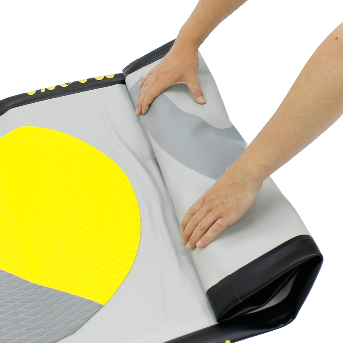 Hände rollen eine grau-gelbe Yogamatte auf. Die Matte liegt auf einer weißen Oberfläche. Schwarzer Rand ist sichtbar.