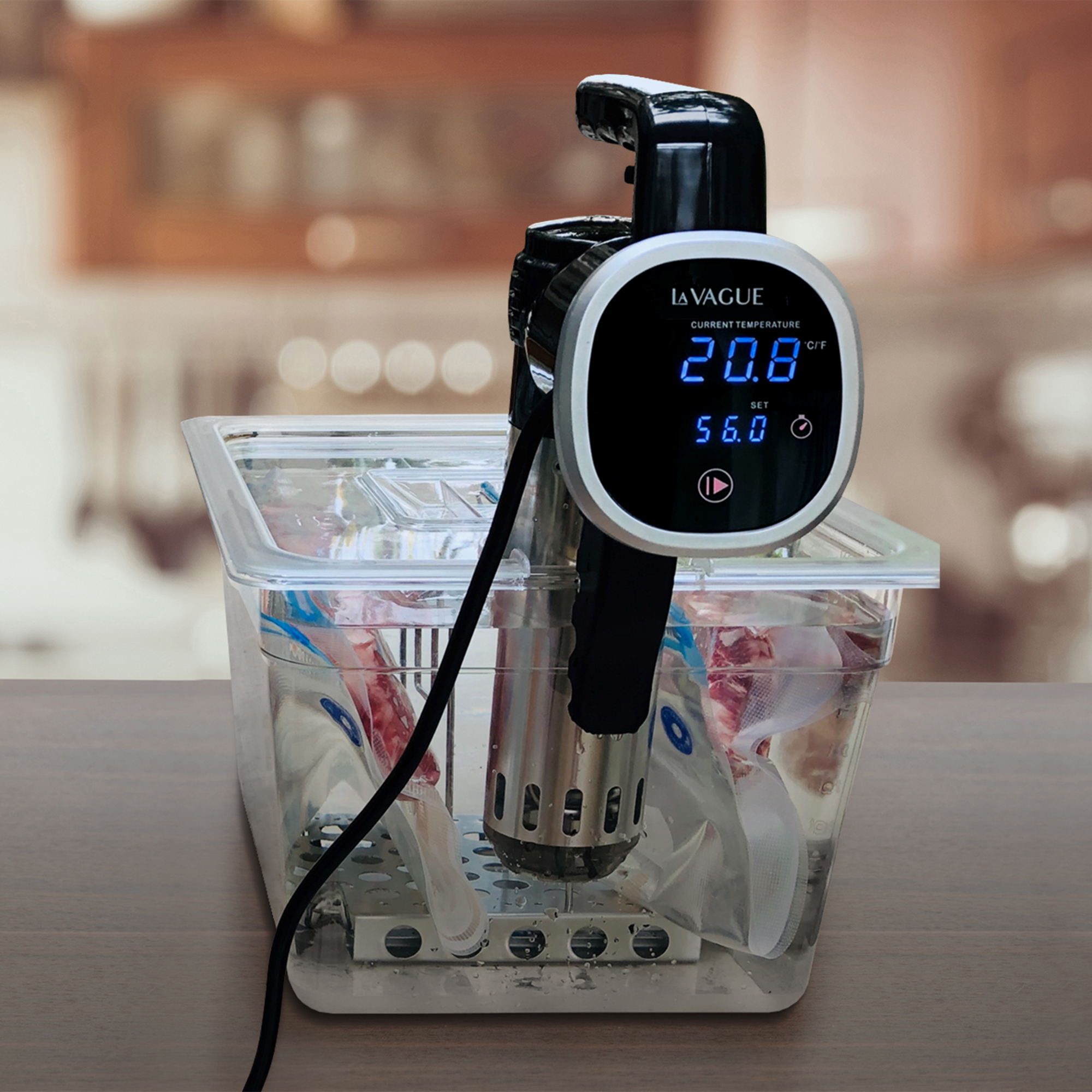 Sous-Vide-Gerät in einem transparenten Behälter mit Wasser und Essen. Holztisch.