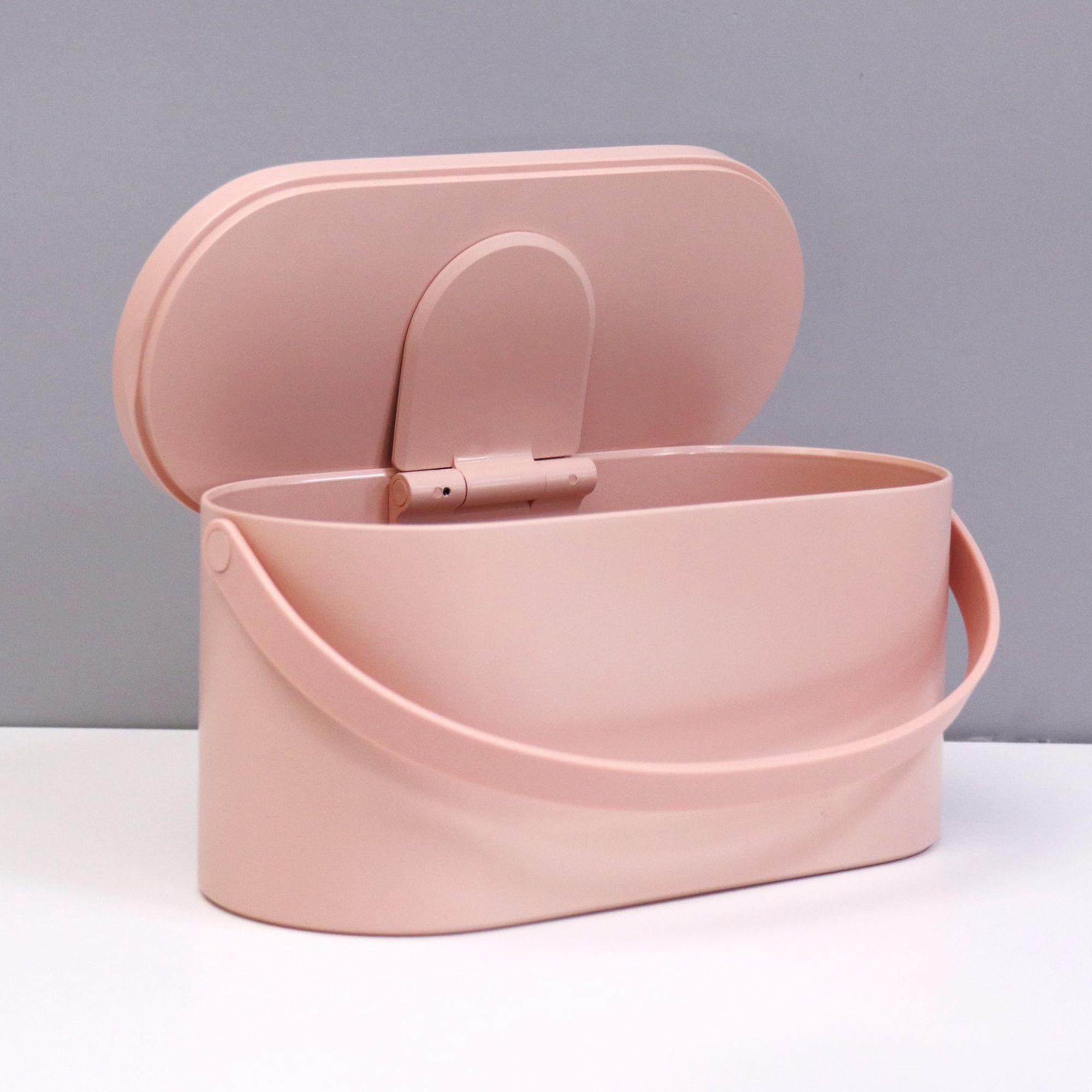 Eine rosa Aufbewahrungsbox mit Griff und offenem Deckel. Der Hintergrund ist grau und weiß.
