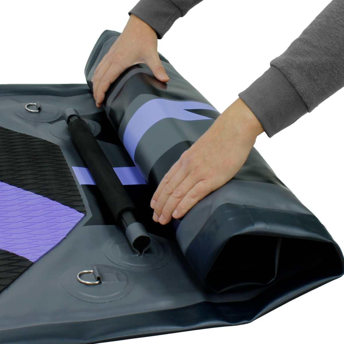 Hände rollen ein Stand-Up-Paddleboard. Das Board ist grau und lila mit schwarzen Details.