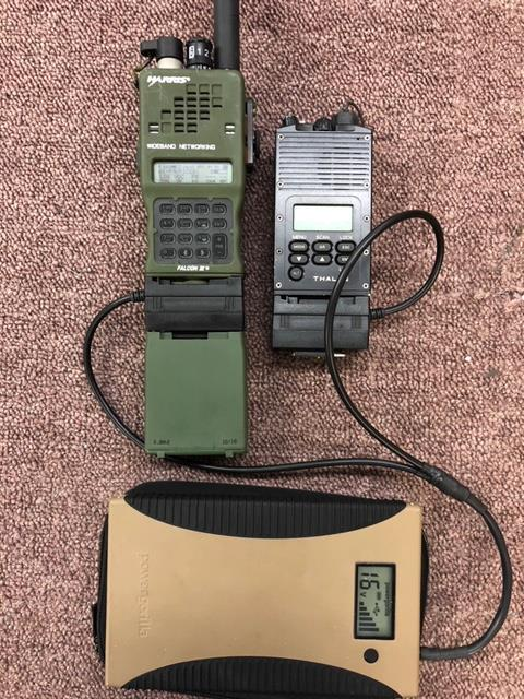 Due radio, una verde, una nera, collegate a un power bank beige su una superficie marrone.