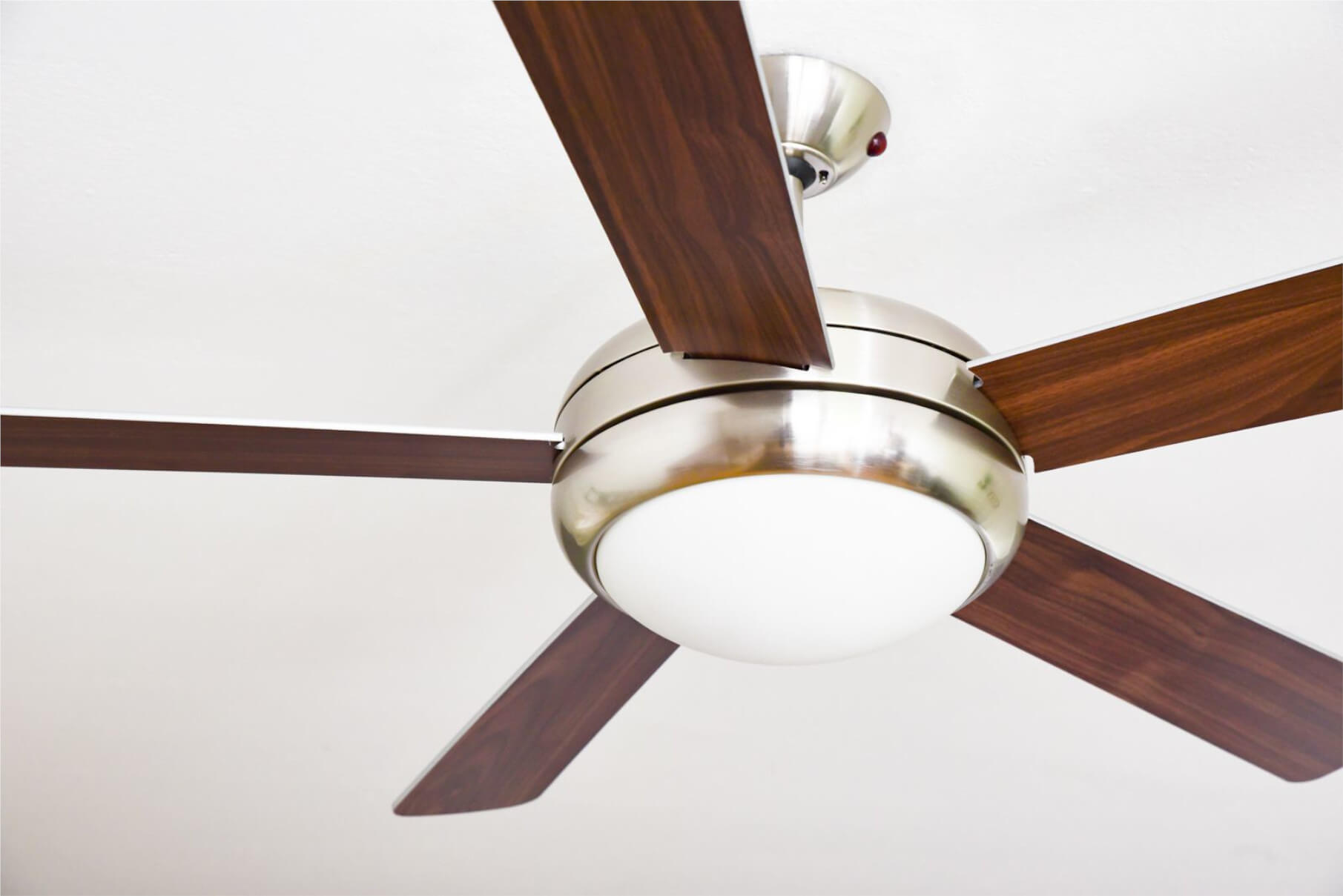 Deckenventilator mit Holzflügeln und einer zentralen Leuchte.