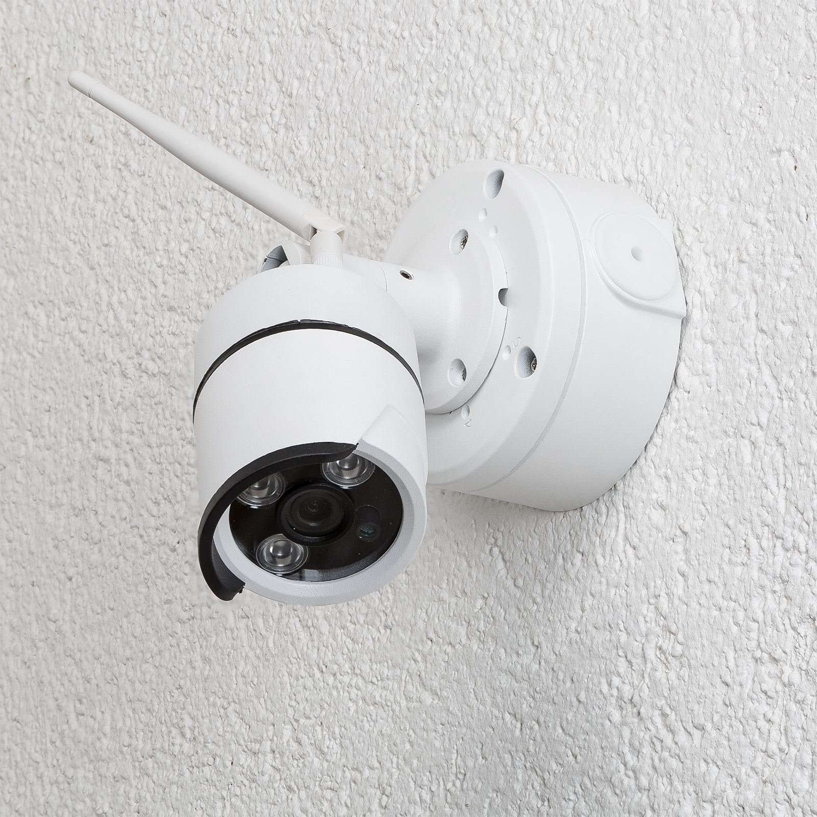 Weiße Überwachungskamera an strukturierter Wand mit Antenne. Nahaufnahme.