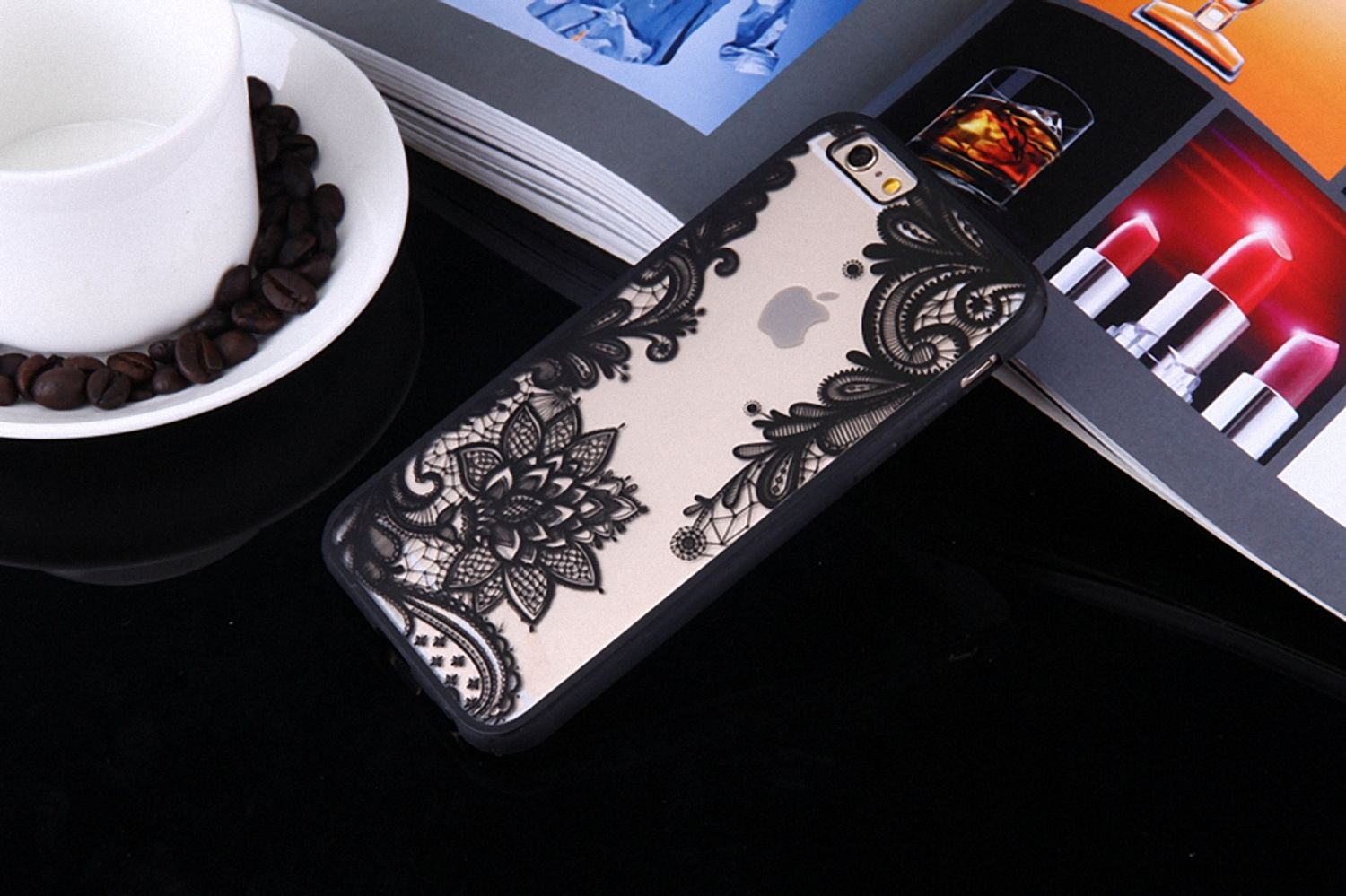 Handyhülle mit floralem Spitzendesign. Das Telefon liegt auf einem Magazin, mit einer Kaffeetasse und Lippenstiften.