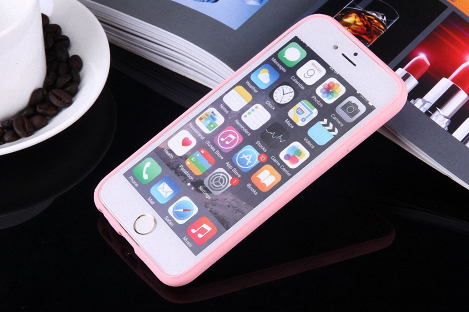 Smartphone in pinkfarbener Hülle auf einem Tisch mit Kaffeebohnen und offenem Buch.