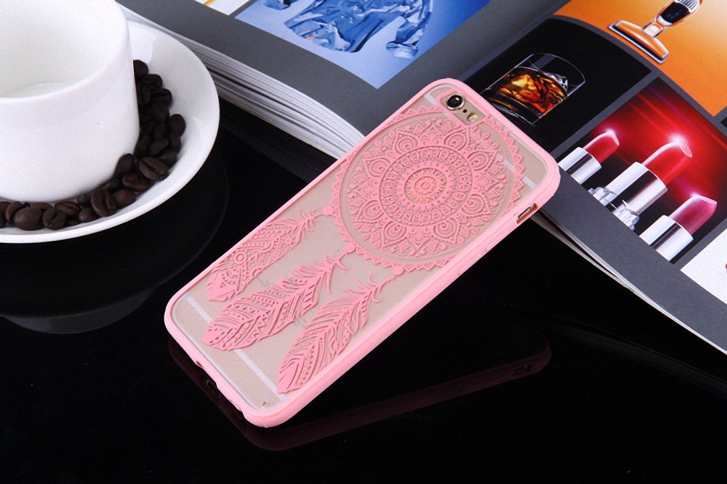 Handyhülle mit rosa Traumfänger-Design. Das Telefon liegt auf einer Zeitschrift. Schwarzer Hintergrund.