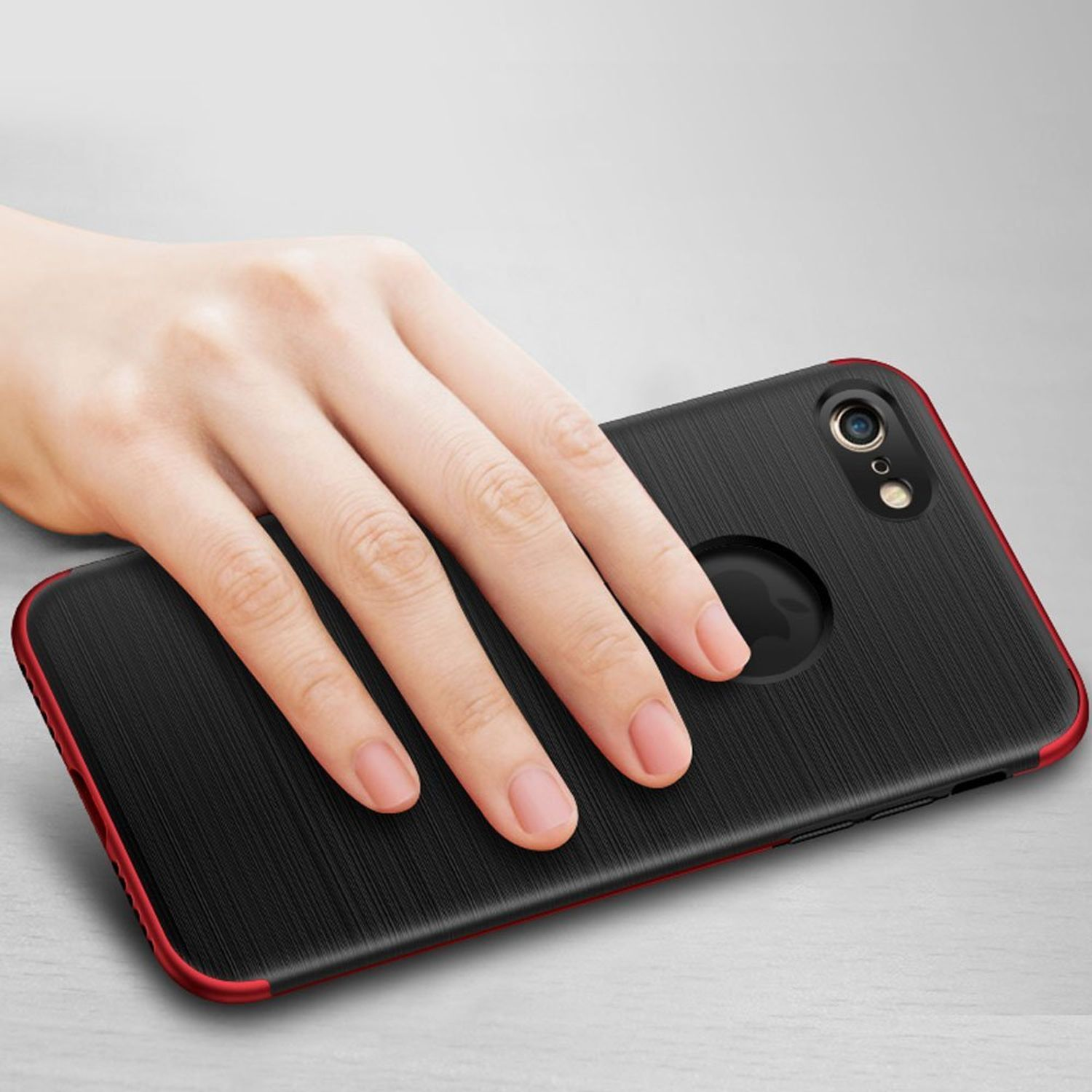 Hand hält eine schwarze Handyhülle mit roter Umrandung. Die Hülle liegt auf einer hellen Oberfläche.