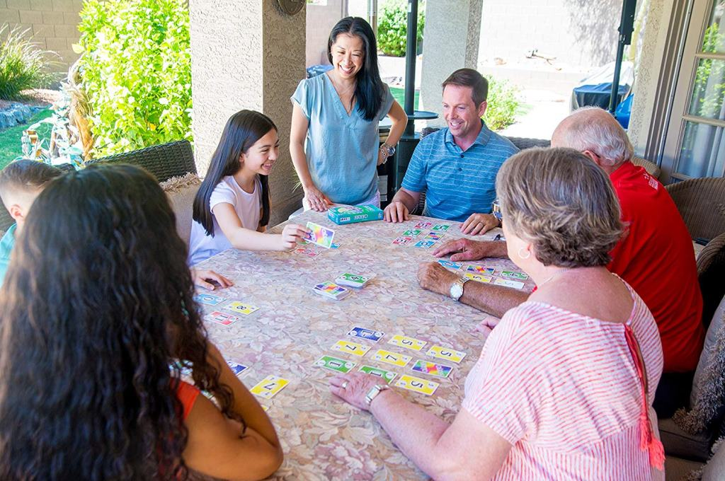 Rodzina gra w karty wokół stołu na zewnątrz pod patio.