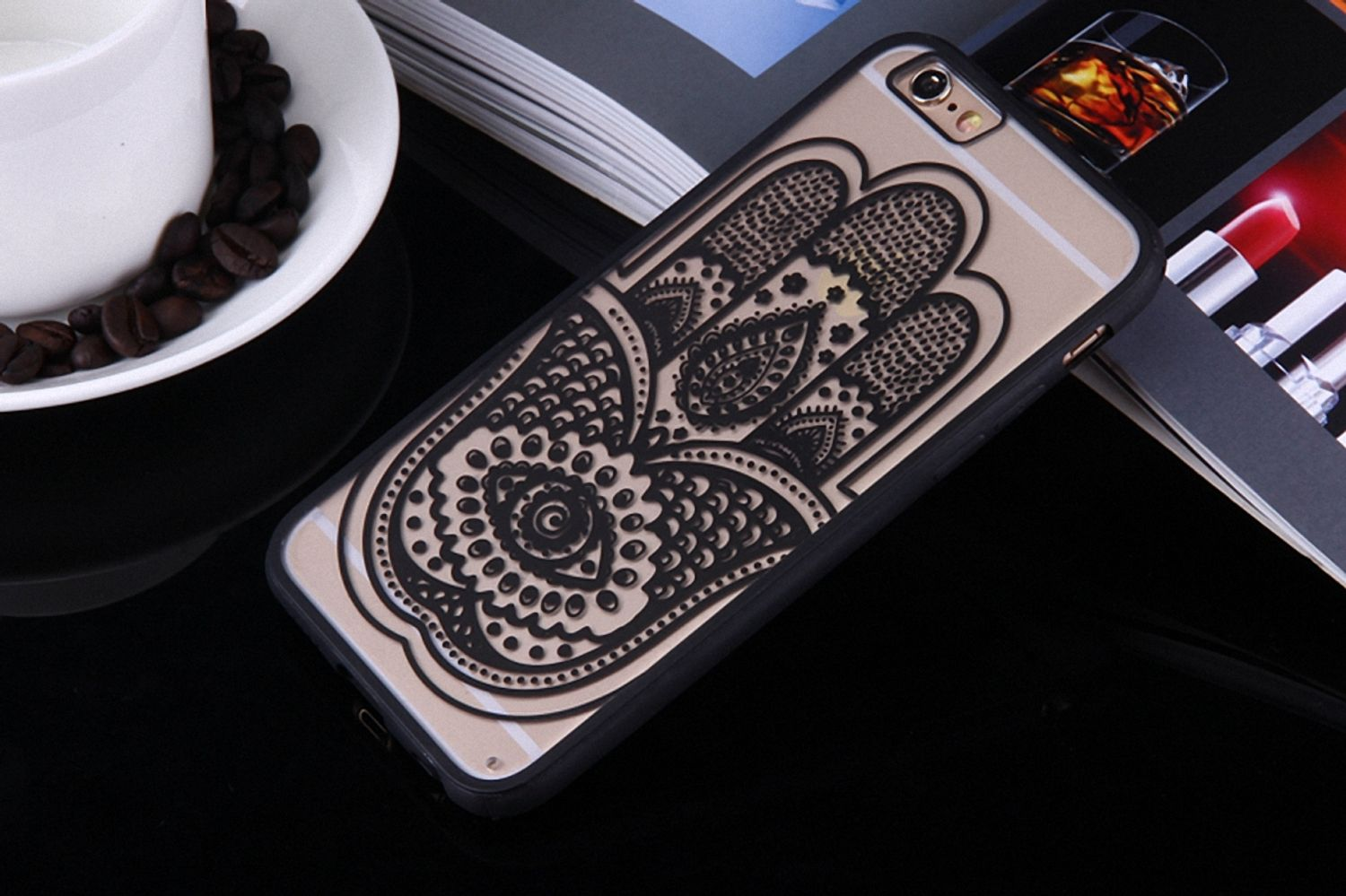 Handyhülle mit Hamsa-Hand-Design, auf glänzender Oberfläche mit weißer Tasse und Kaffeebohnen.