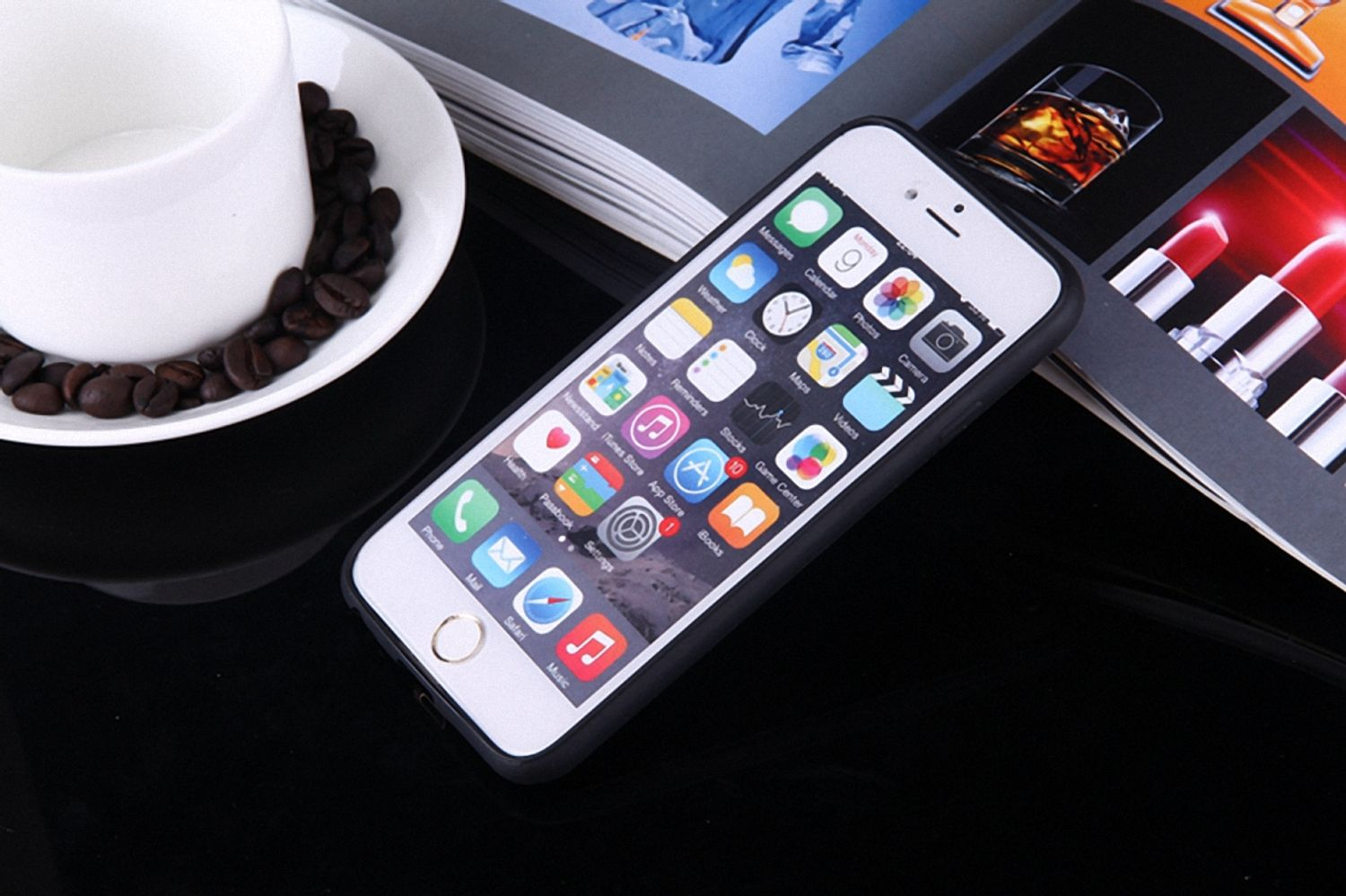 Smartphone mit App-Symbolen, Kaffeetasse und Magazin auf dunkler Oberfläche.