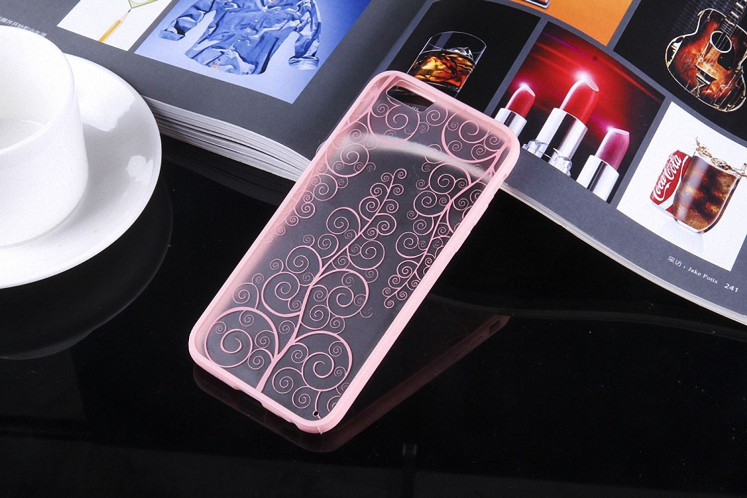 Rosa Handyhülle mit Wirbeldesign auf Zeitschrift mit Lippenstift und Getränk.