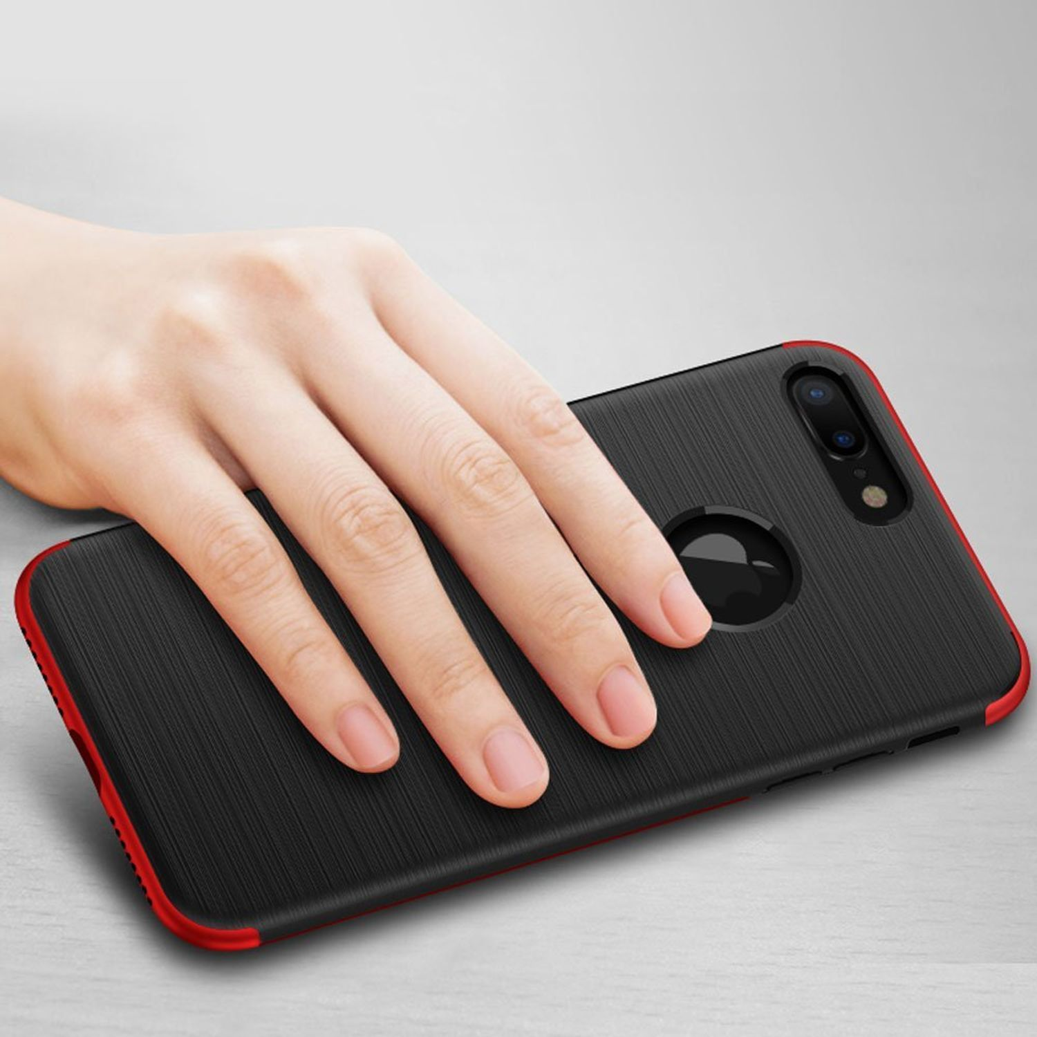 Schwarze Handyhülle mit rotem Rand, gehalten von einer Hand. Das Telefon liegt auf einer hellen Oberfläche.