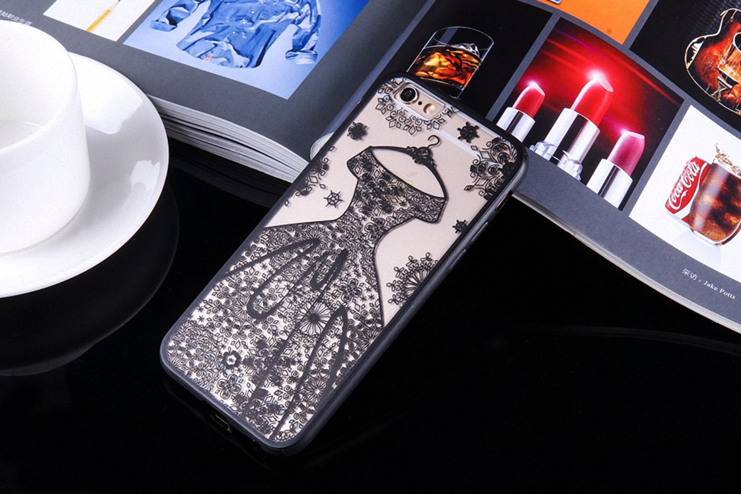Ein Smartphone liegt auf einem Tisch mit schwarzer Hülle. Die Hülle zeigt ein Kleid-Design mit Schmetterlingen.