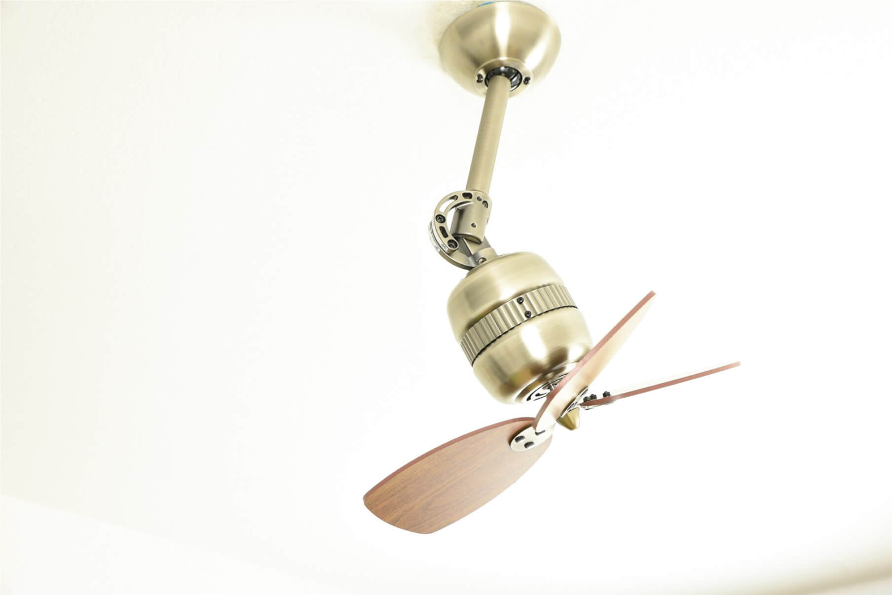 Ventilatore a soffitto, finitura oro, pale in legno, appeso al soffitto.