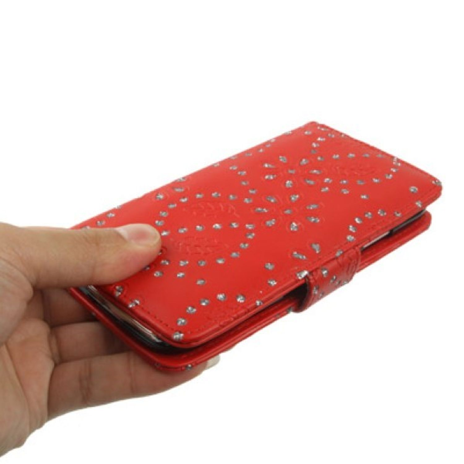 Hand hält eine rote Handyhülle mit silbernen Nieten und gemustertem Design auf weißem Grund.