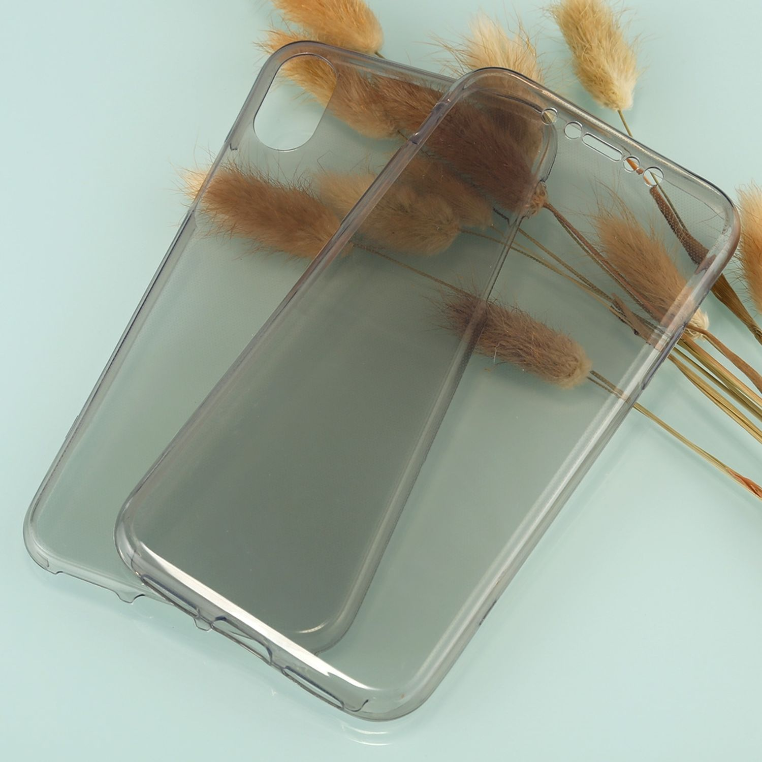Zwei transparente Handyhüllen auf hellblauem Untergrund, mit getrockneten Blumen.