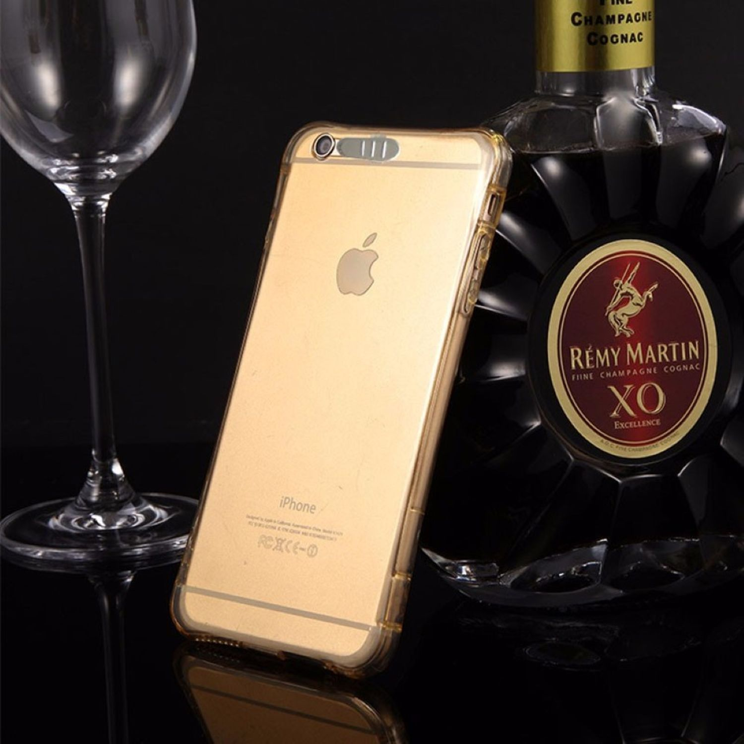 Goldenes iPhone in einer durchsichtigen Hülle, neben einem Weinglas und einer Rémy Martin Flasche.