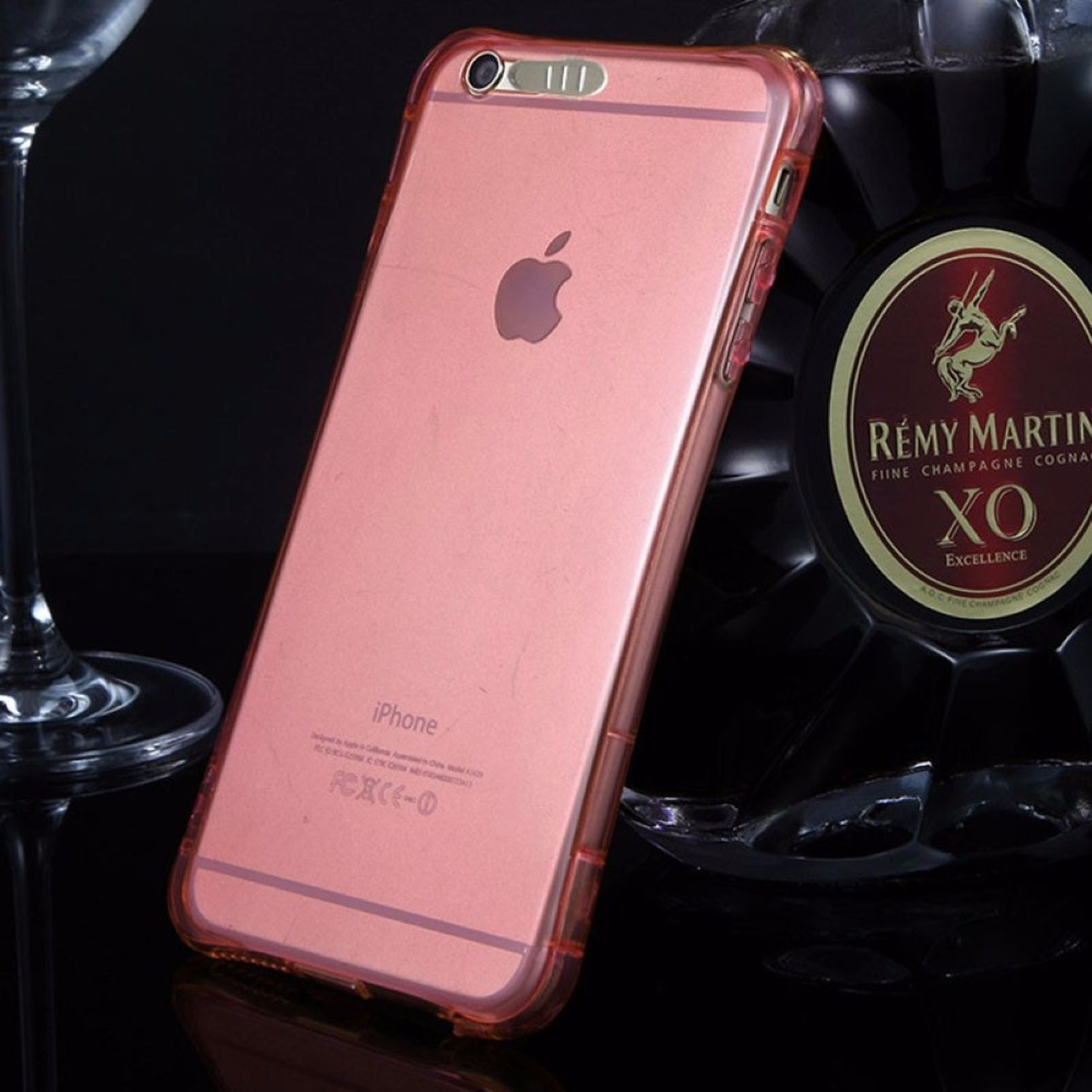 Ein Telefon in einer rosa Hülle neben einer Flasche Rémy Martin Cognac und einem Glas.