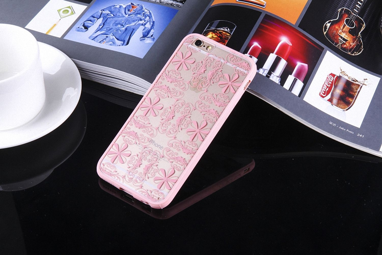 Telefon mit rosa Hülle mit Blumendesign. Das Telefon liegt auf einem Tisch mit anderen Objekten.