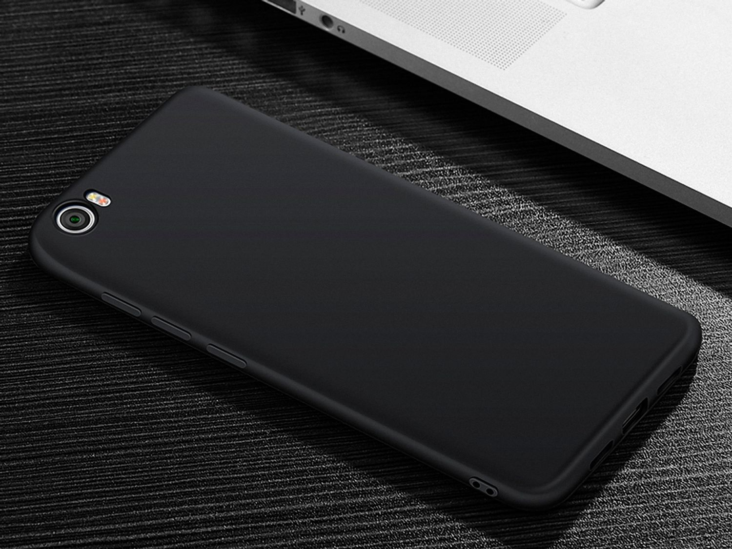 Schwarze Handyhülle. Das Telefon liegt auf einer schwarzen Oberfläche. Draufsicht.