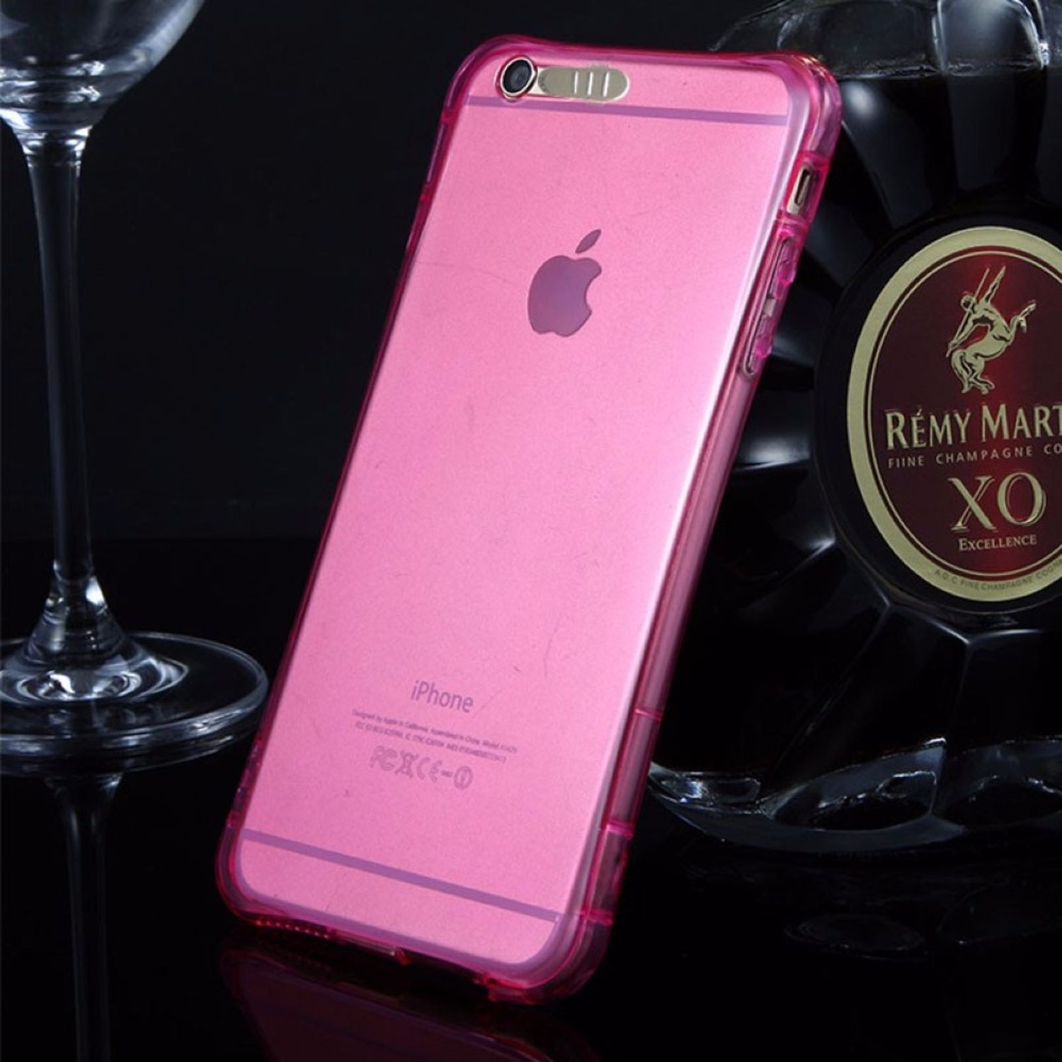 Rosa iPhone-Hülle. Flasche Remy Martin und Glas im Hintergrund. Apple-Logo sichtbar.