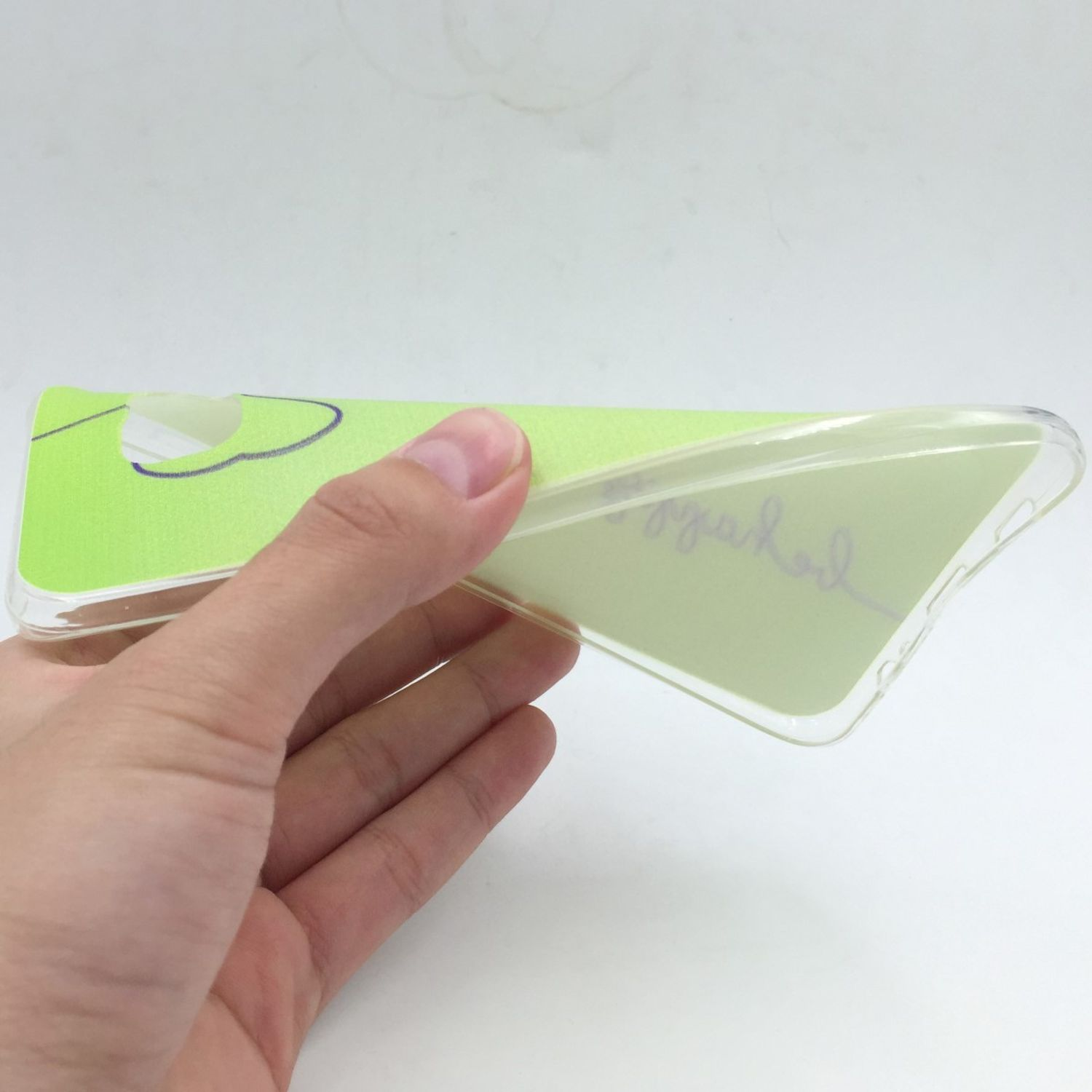 Eine Hand hält eine transparente Handyhülle mit grünem Design.