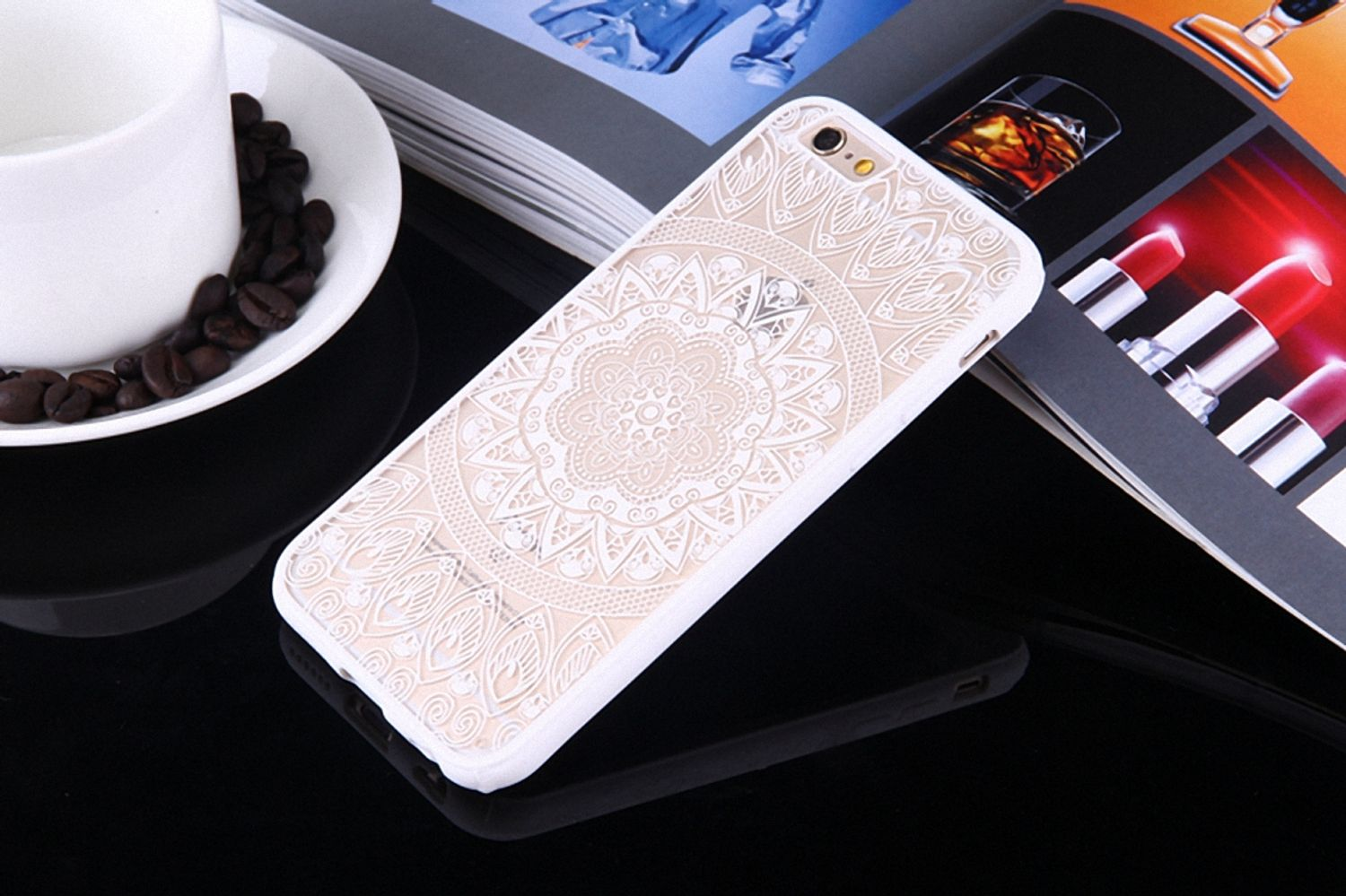 Telefon in weißer Hülle mit Blumenmuster. Das Telefon liegt auf einer reflektierenden schwarzen Oberfläche.