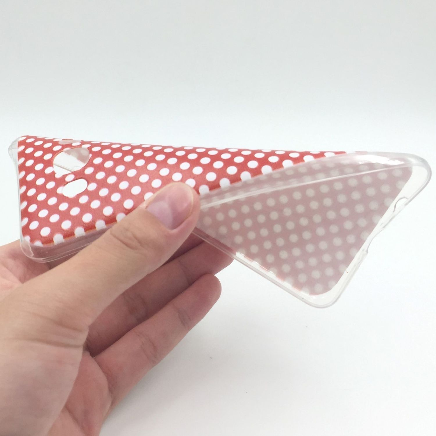 Hand hält eine transparente Handyhülle mit roten Punkten.