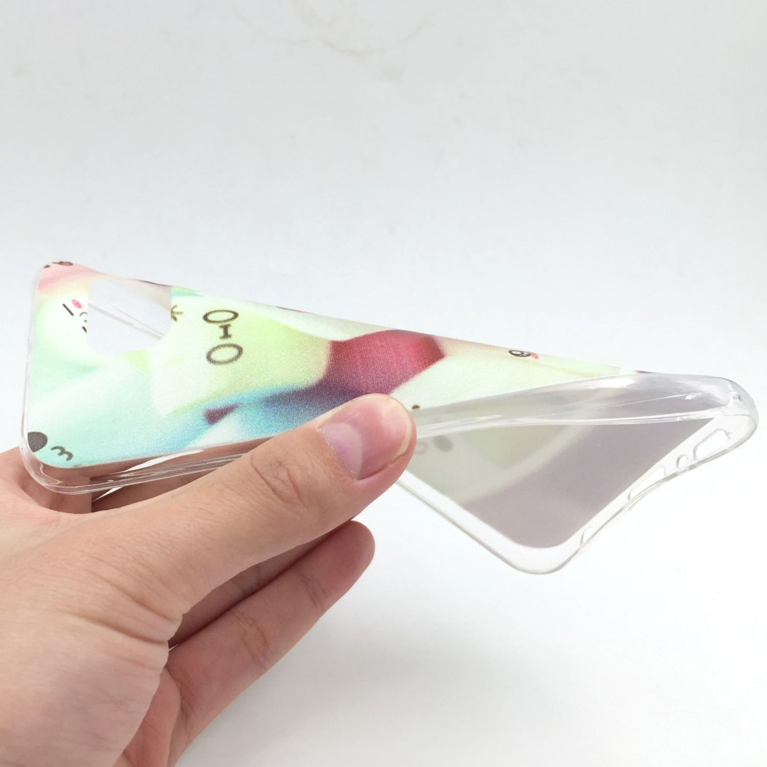 Hand hält eine transparente Handyhülle mit buntem Design.