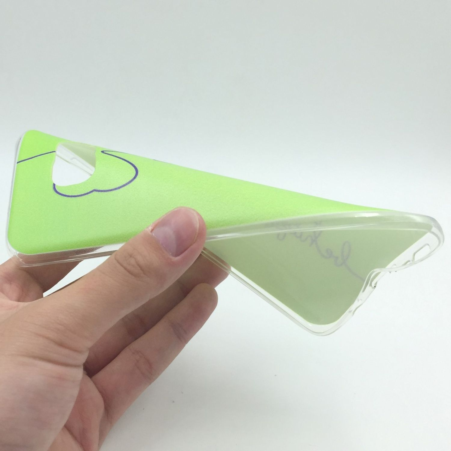 Hand hält grüne Handyhülle. Die Hülle hat ein Design und ist durchsichtig.