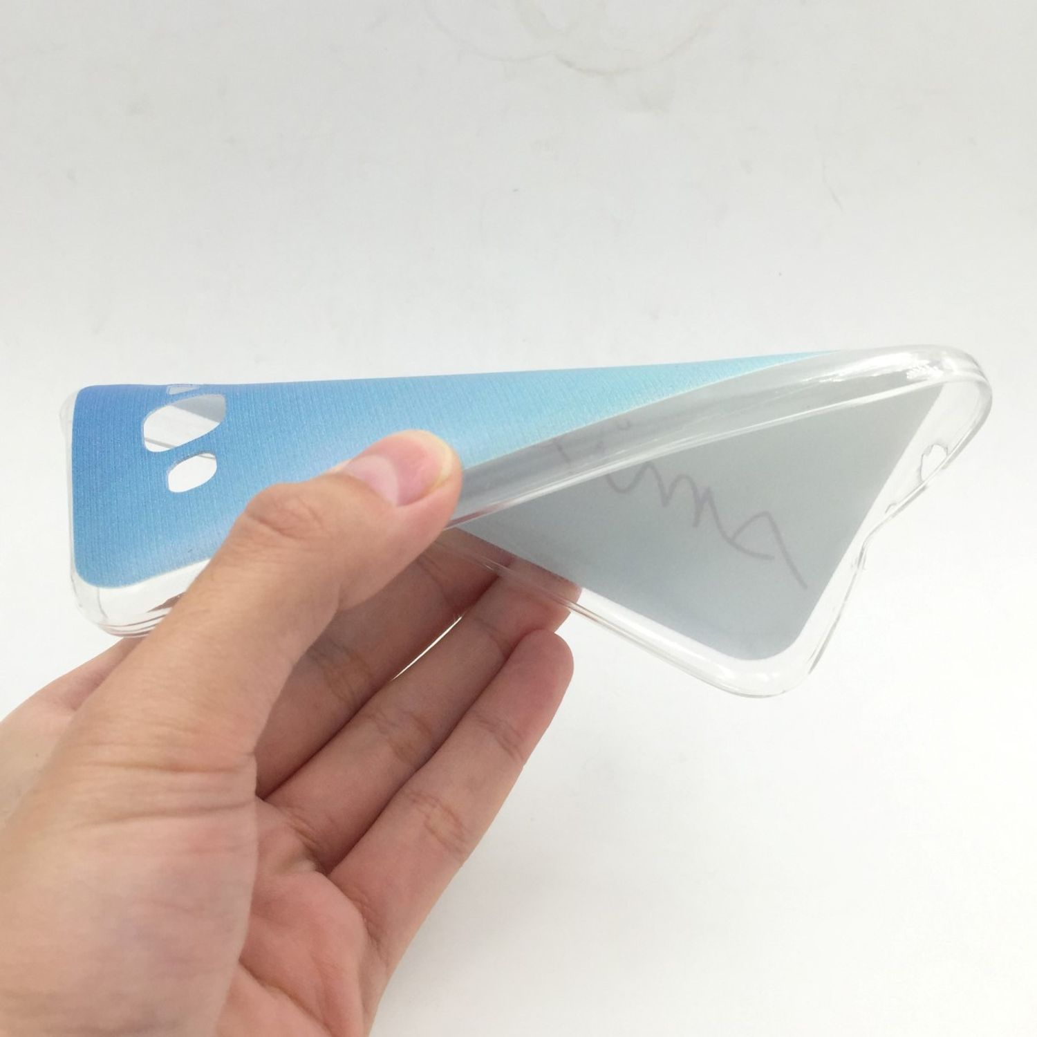 Hand hält transparente Handyhülle mit hellblau-weißem Design auf der Rückseite. Weißer Hintergrund.