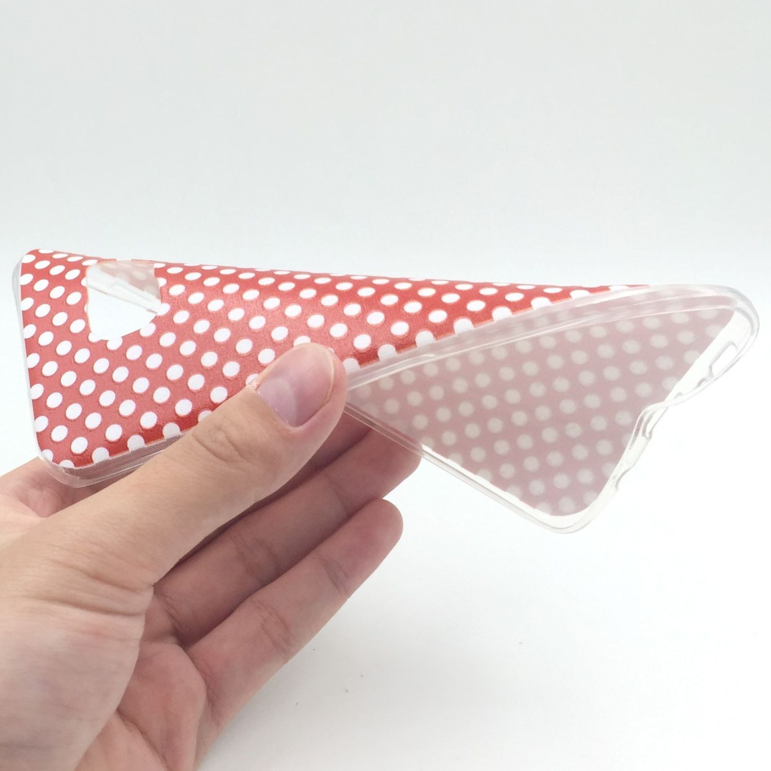 Hand hält eine klare Handyhülle mit weißen Punkten auf rotem Hintergrund.