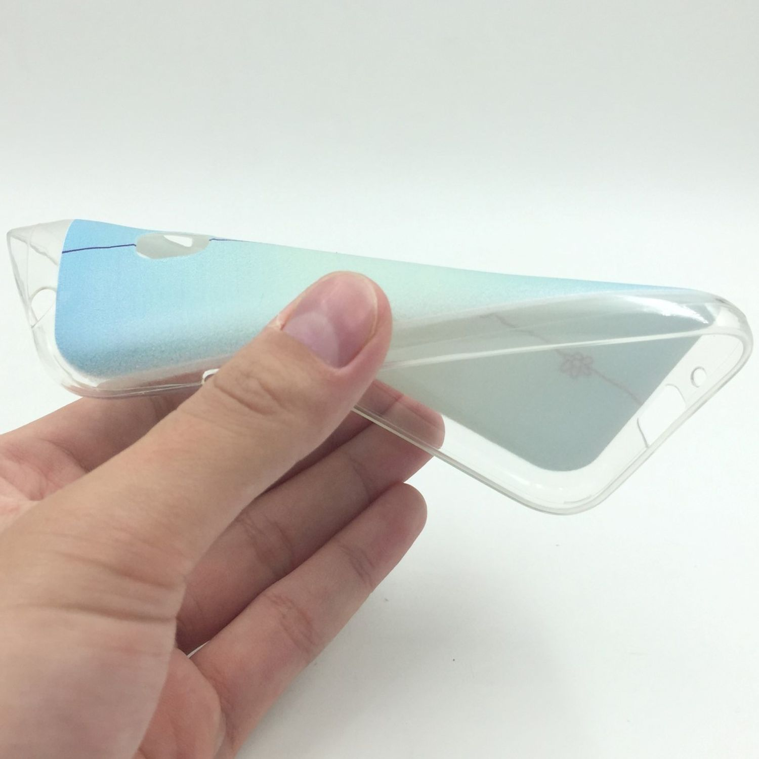 Hand hält eine transparente Handyhülle mit blau-grünem Farbverlauf. Der Hintergrund ist weiß.