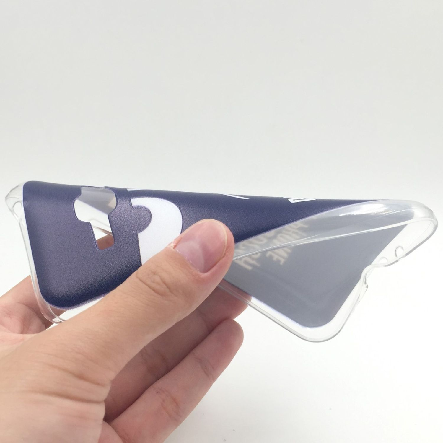 Hand hält eine transparente Handyhülle mit blauem Design, klarer Hintergrund.